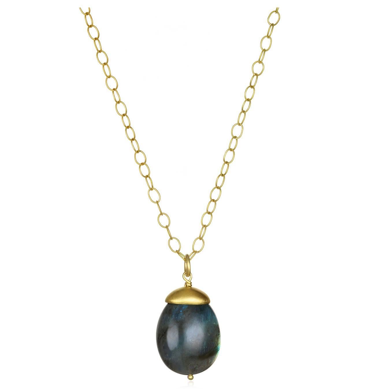 Labradorite is treasured for its sensational play of color.  Our pendant has iridescent flashes of peacock blue, gold and green.  It's finished with a handmade dome cap in 18k green* gold and is 1.5" long.  The 18k gold oval link chain is