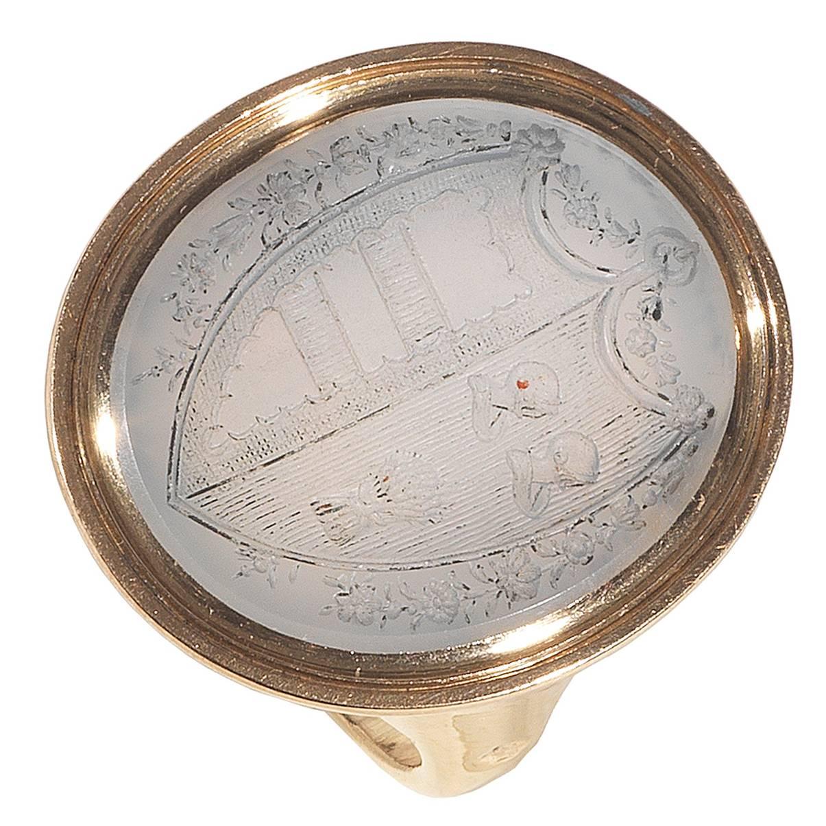 
PLEASE NOTE: OUR PRICE IS FULLY INCLUSIVE OF SHIPPING, IMPORTATION TAXES & DUTIES.

The oval shaped bezel with white chalcedony intaglio engraved with a coat of arms depicting a shield shaped crest divided in two sections, one of which