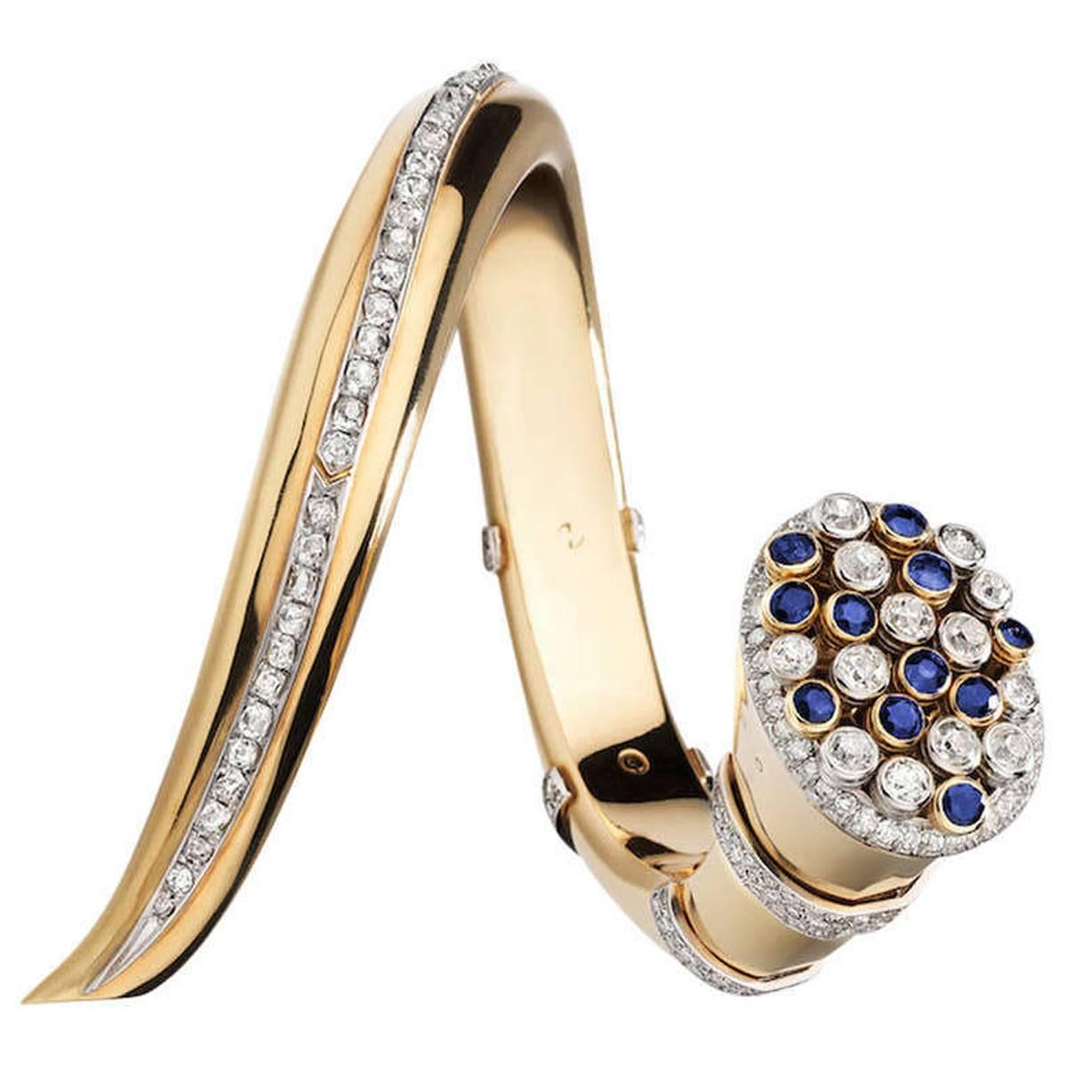 Unique and Monumental! The cluster of oval and circular-cut sapphires and diamonds is set en tremblant within the open terminal, framed by circular-cut stones, the bangle embellished with a row and bands of cushion-shaped, circular- and single-cut