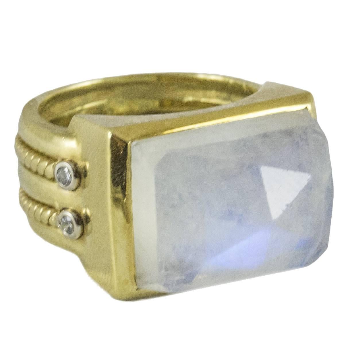 A unique vintage moonstone ring set in 18kt yellow gold. The moonstone is faceted and reflects luminous colours from the surrounding environment. It has a wide custom made band with intricate rope detailing finished by four bright brilliant cut