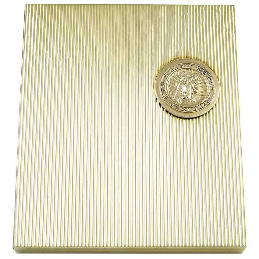 Outstanding traveling picture frame.  Made and signed by CARTIER.   Allover deep engine-turned lined pattern, with an applied St. Christopher's medal near the clasp.  The frame can stand on its own, or be used folded for travel.  Opens to reveal