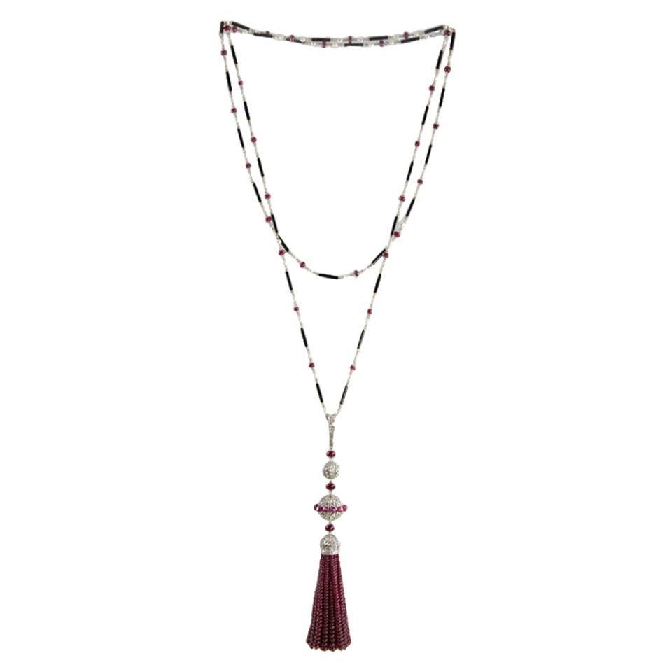 The tassel is composed of 15 strands of ruby beads attached to a pierced, diamond-set cap, ruby beads, round pierced diamond-set balls, 1 decorated with ruby beads and a diamond-set bale. The chain is composed of alternating pearls, ruby beads and