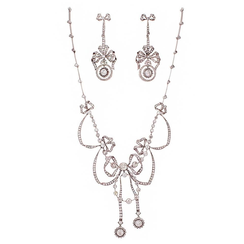 Platinum and diamond necklace and earrings of handmade construction and Exquisite workmanship in original box. The necklace and earrings are done in the garland style; necklace featuring diamond set bows, ribbons, flowers, flexible links and chains