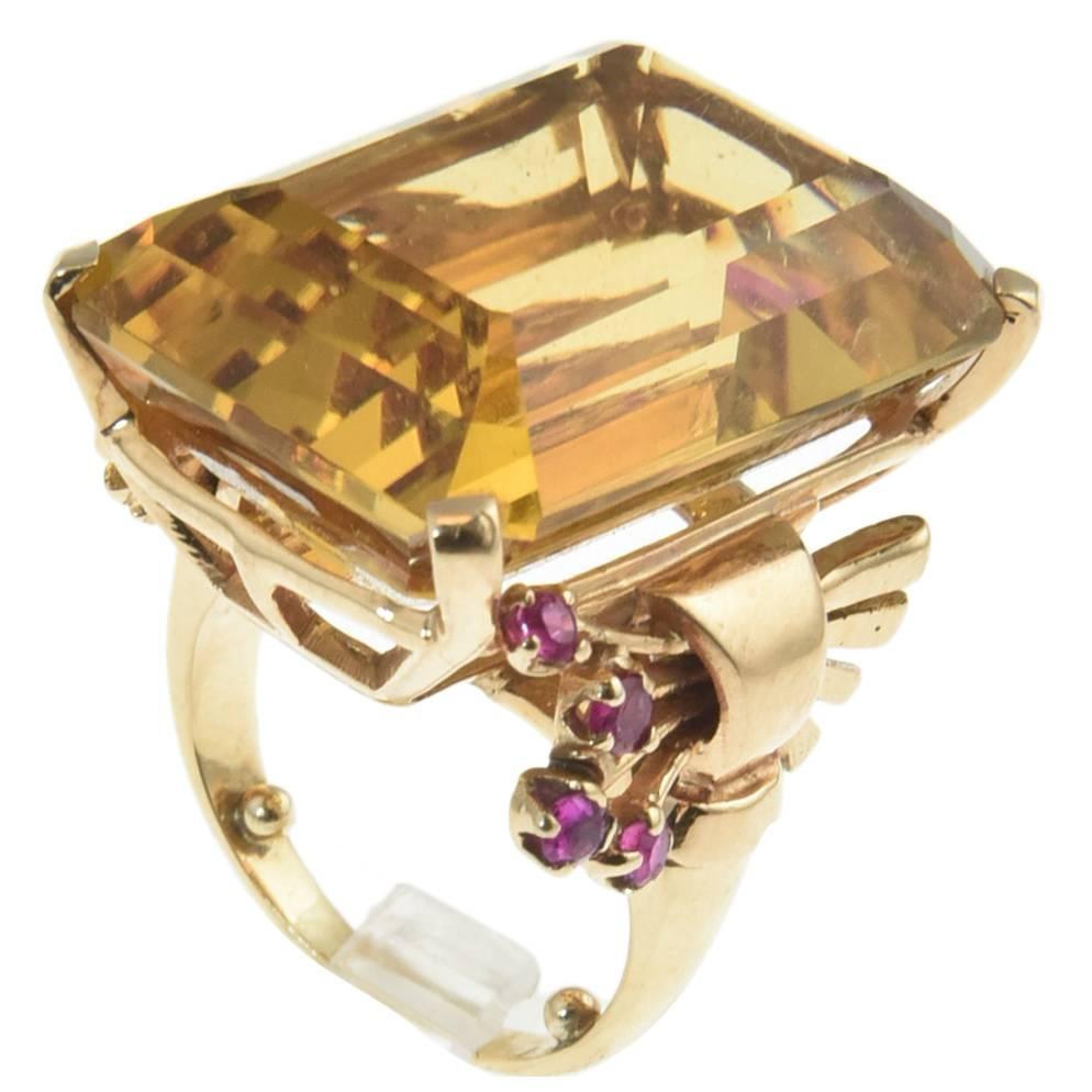 1940's Retro Ring featuring a large 45 carat  Citrine with a floral ruby scrolls on the band on either side.  The ring is 14k rose gold.

US size 7.25.  It can be sized