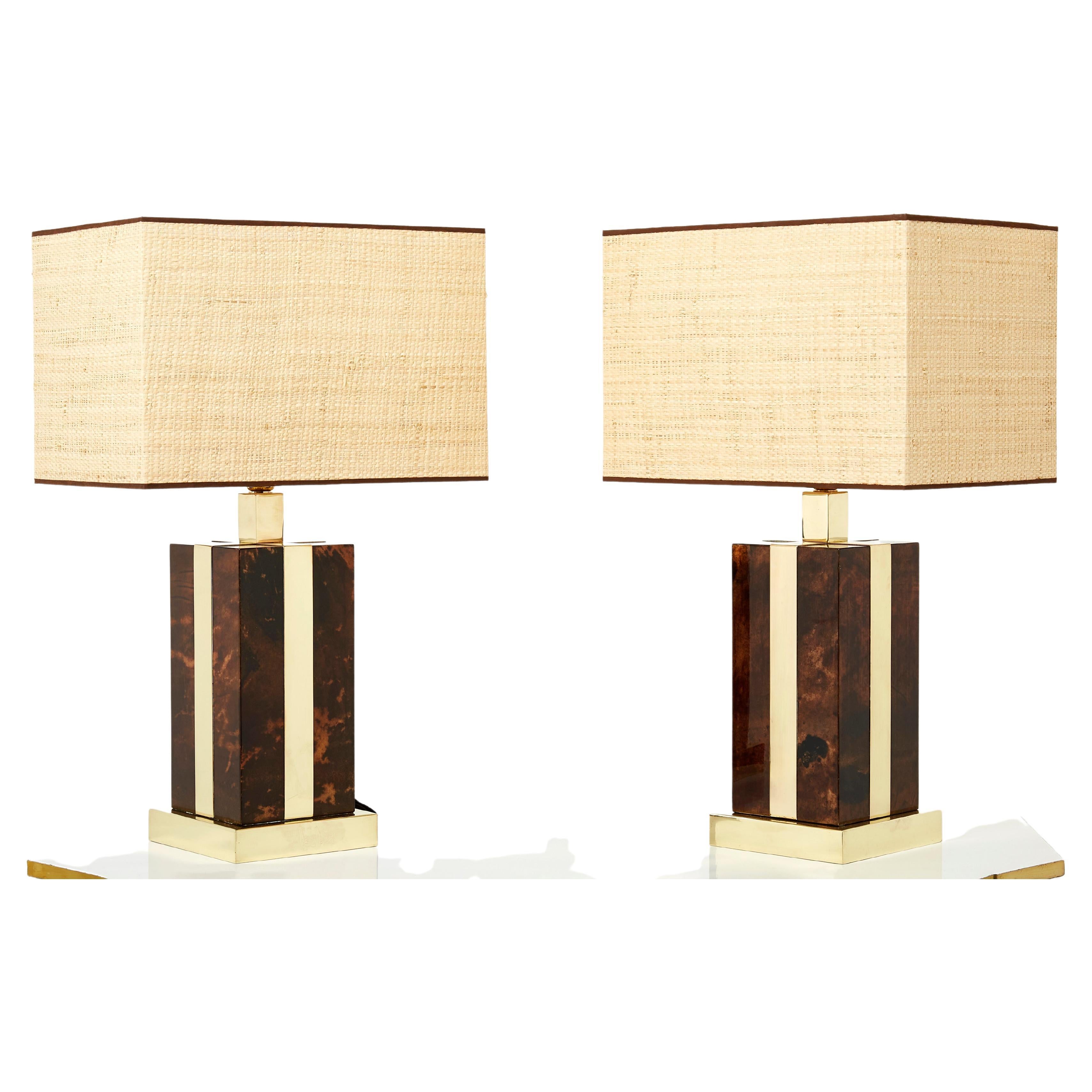 This pair of Aldo Tura Italian goatskin and brass table lamps were made in the early 1970s. They feature a varnished goatskin parchment, in rich shades of light to dark brown, typical of Aldo Tura’s work, with brass inlays on each side, topped with