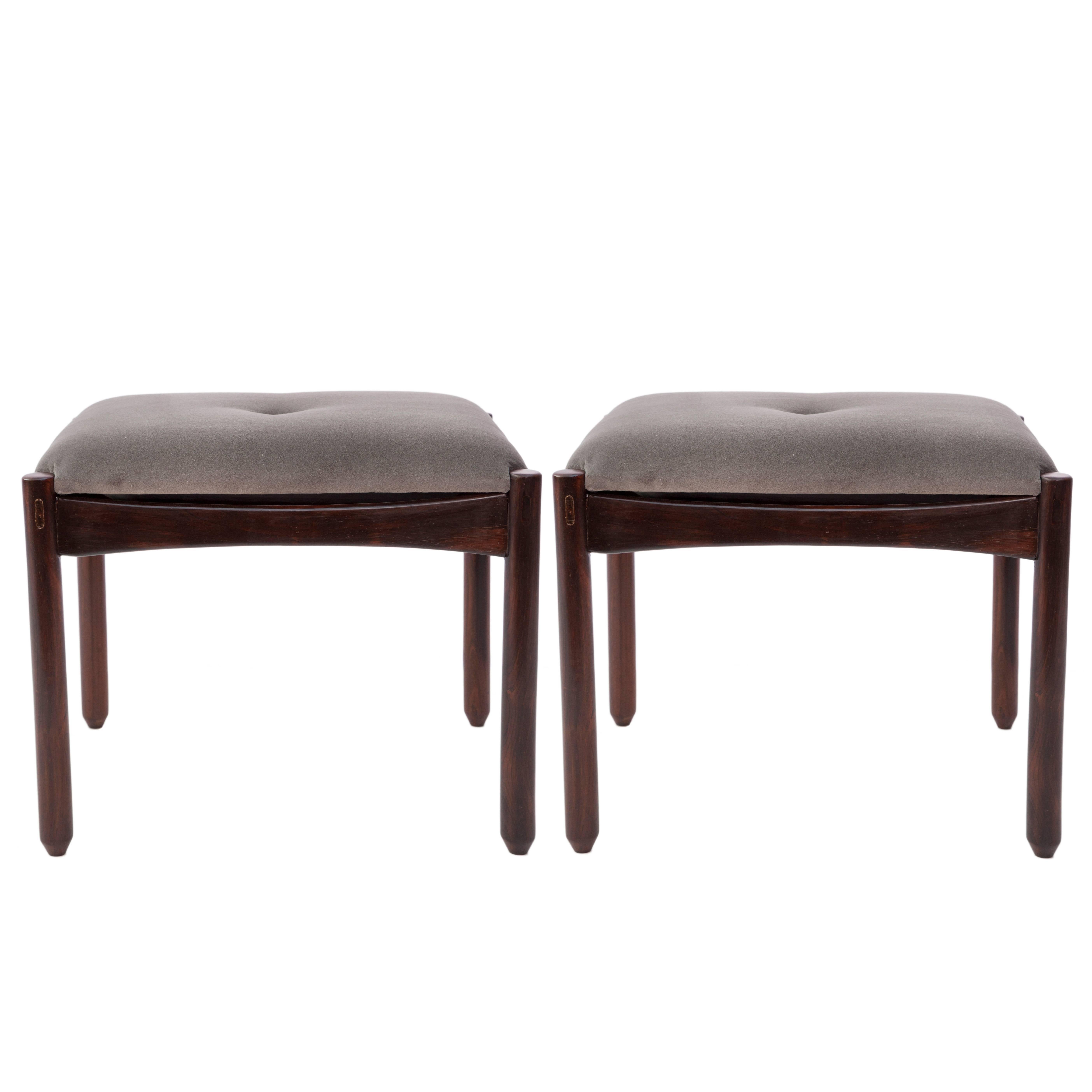 A pair of stools by Sergio Rodrigues, produced circa 1960s, with tufted grey cotton velvet seats, on Brazilian jacaranda wood bases and turned, cylindrical wooden legs. Very good vintage condition, consistent with age and use; seats re-upholstered