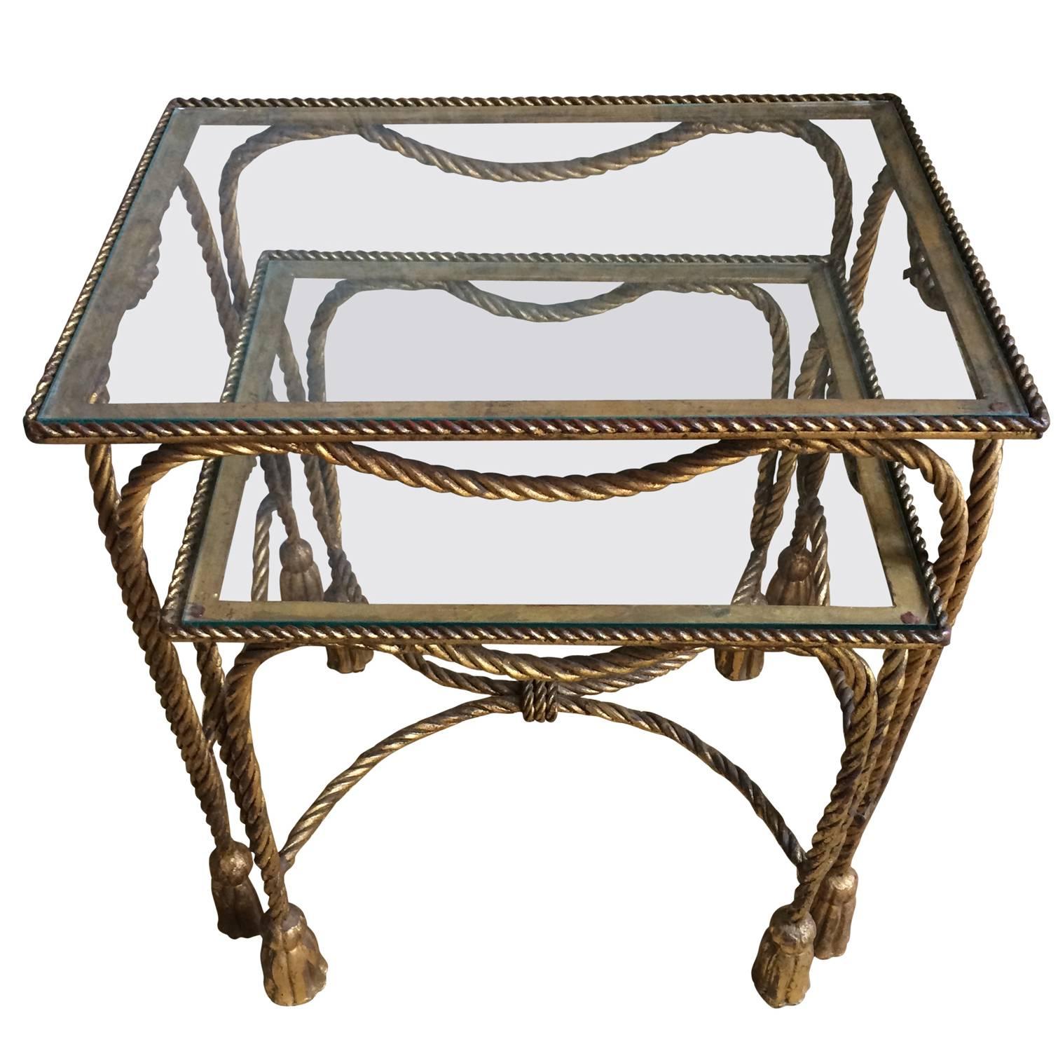 Sophisticated and functional pair of gilt nesting tables with rope detail and tassels. A wonderful traditional set, however a compliment to modern settings as well, the Hollywood Regency style pair are well suited for the guest room, bedroom or den.