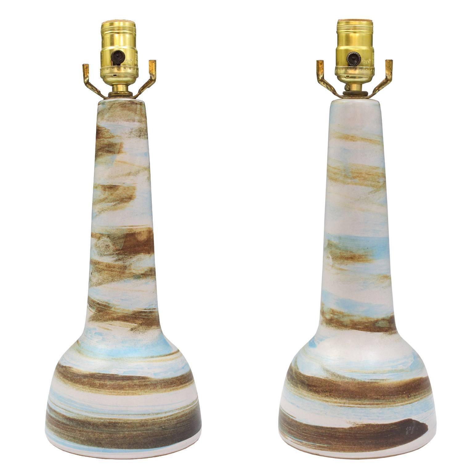 A pair of vintage table lamps, by ceramicist Gordon Martz  for Marshall Studios circa 1950s, each with single sockets over baluster form ceramic bodies, with matte glazed in swirling tones of blue, brown and cream. Markings include artist's