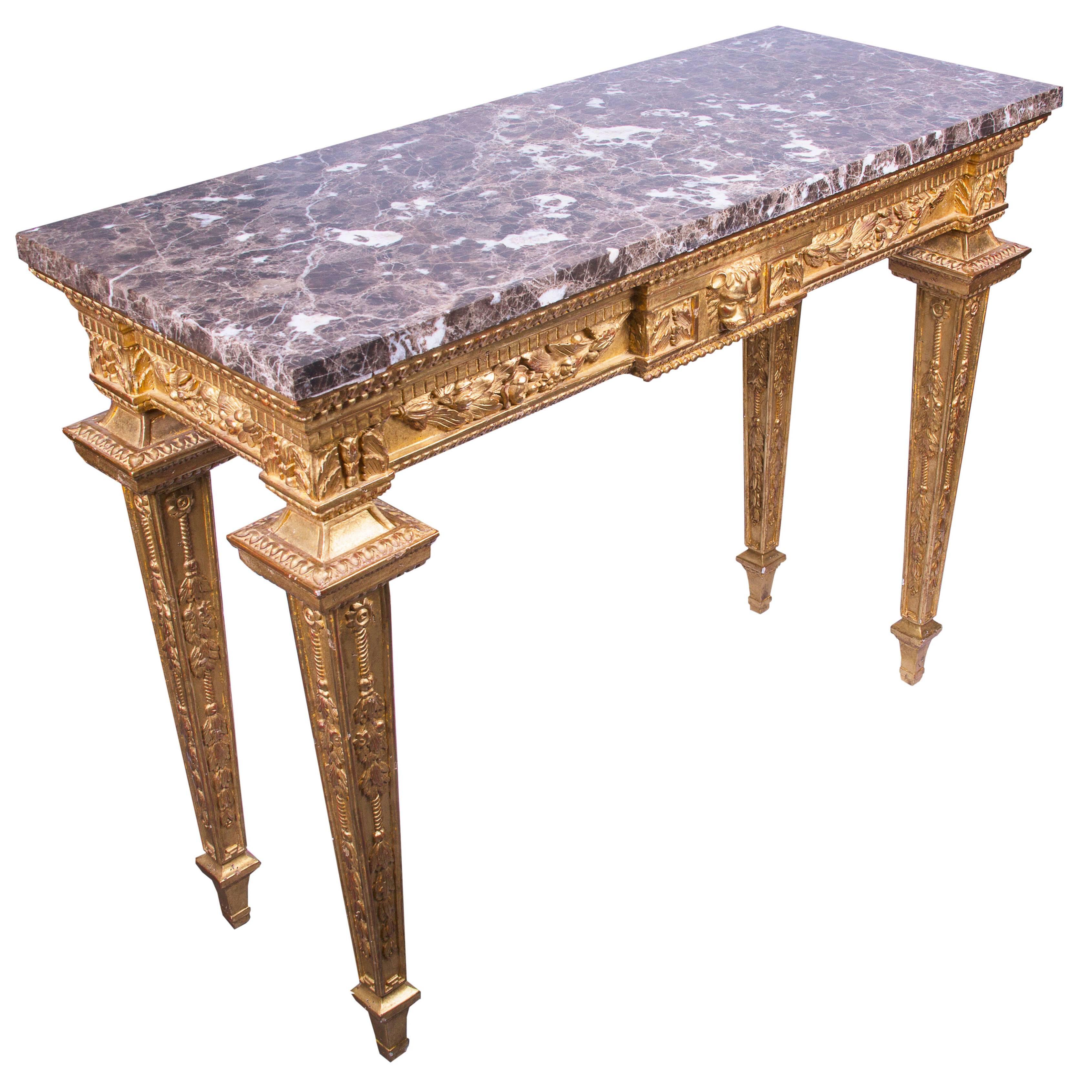 Louis XVI style giltwood console contains variegated marble top over frieze and straight tapered legs, all showing detail in relief form. Central lion mask flanked by swags, 20th century.