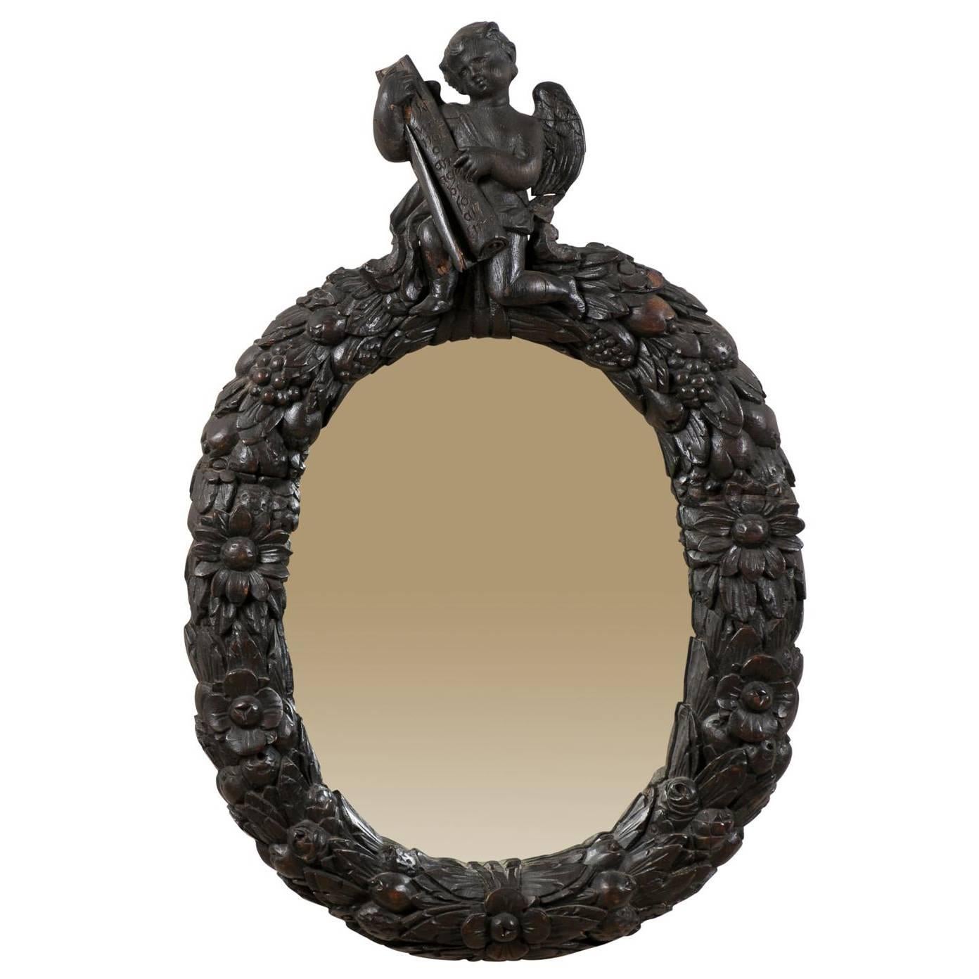 An 18th Century English Oval Richly Carved Deep Brown Colored Wood Wall Mirror For Sale