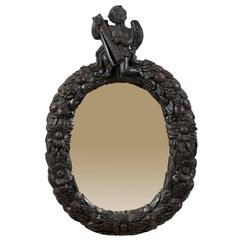 An 18th Century English Oval Richly Carved Deep Brown Colored Wood Wall Mirror