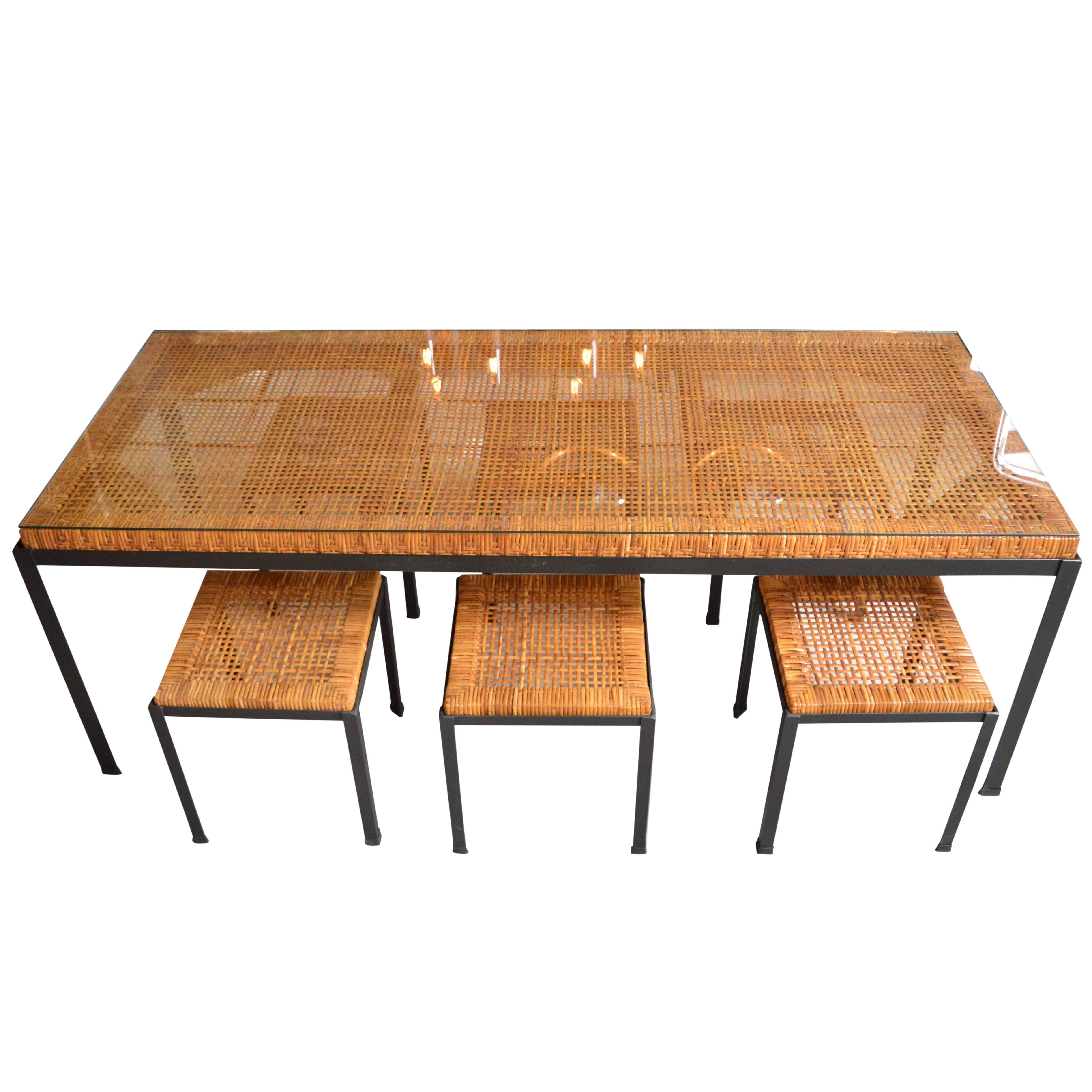 Classic vintage iron and rattan dining table by Danny Ho Fong for Tropi-cal. Set includes six matching stools. Newly cut glass tabletop to protect rattan surface. Excellent vintage condition to rattan. Great patina to iron. Perfect for indoors or