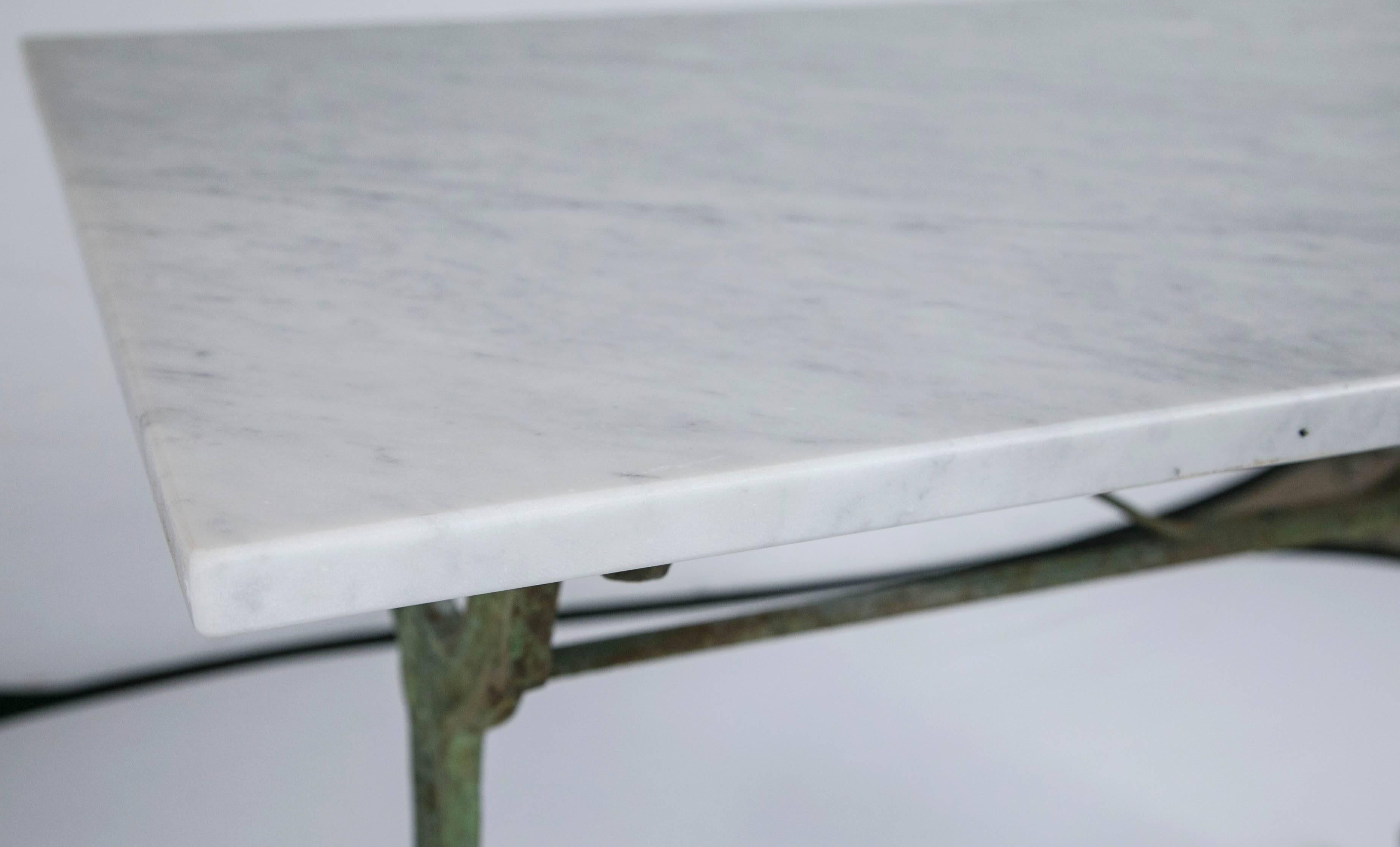 Weathered pale green painted iron base with floral design details. New Carrara marble top.