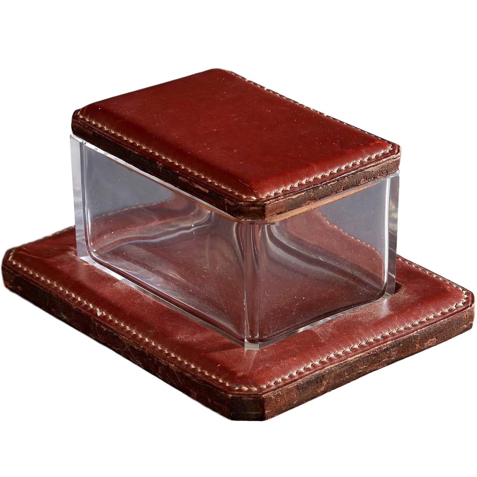 Handsome leather box by French designer Jacques Adnet. Red Leather base with rectangular glass box and red leather lid. Signature contrast stitching. Excellent vintage condition.