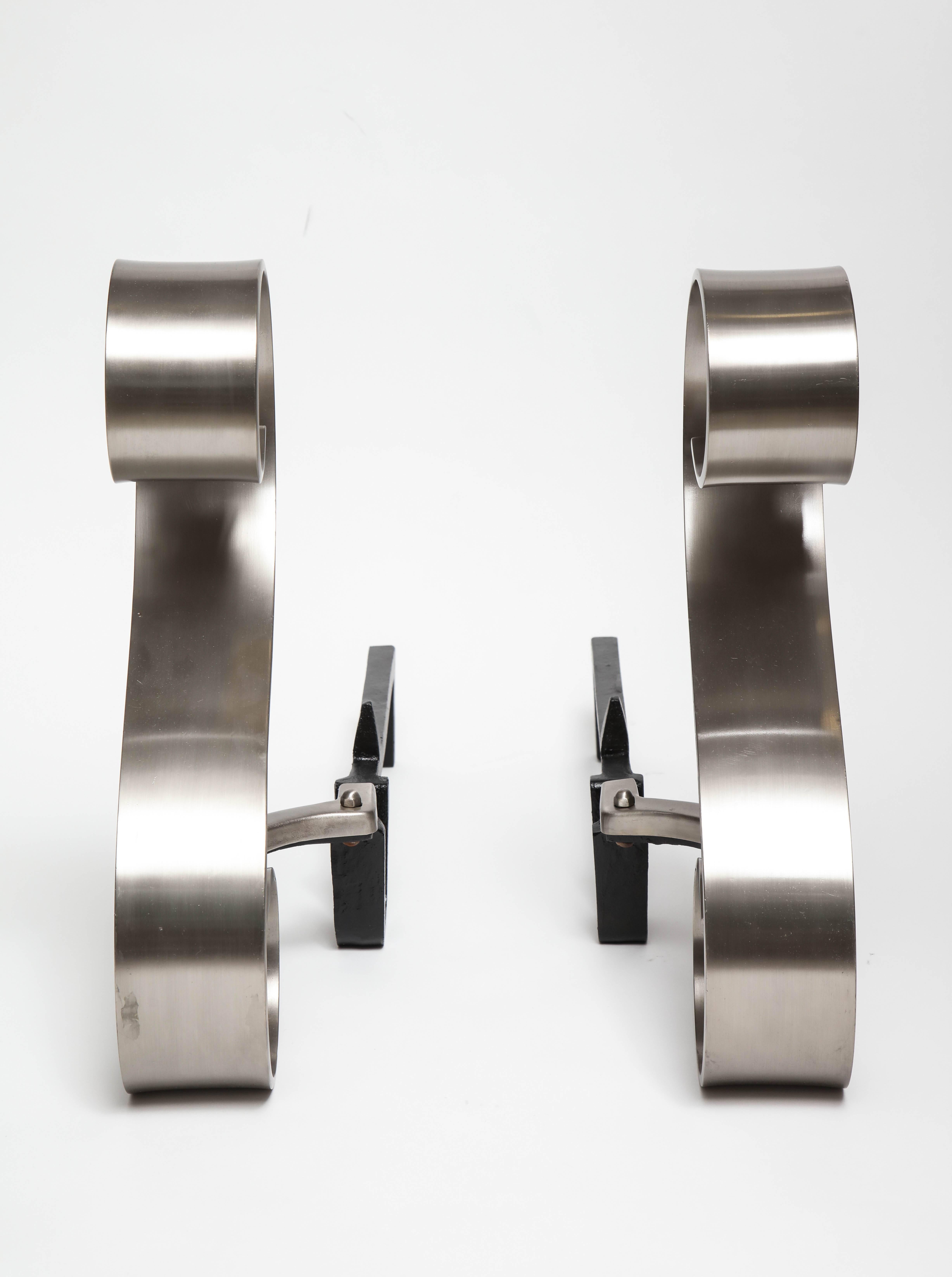 Pair of graceful Art Deco scroll motif andirons in a brushed nickel finish with black iron backs.