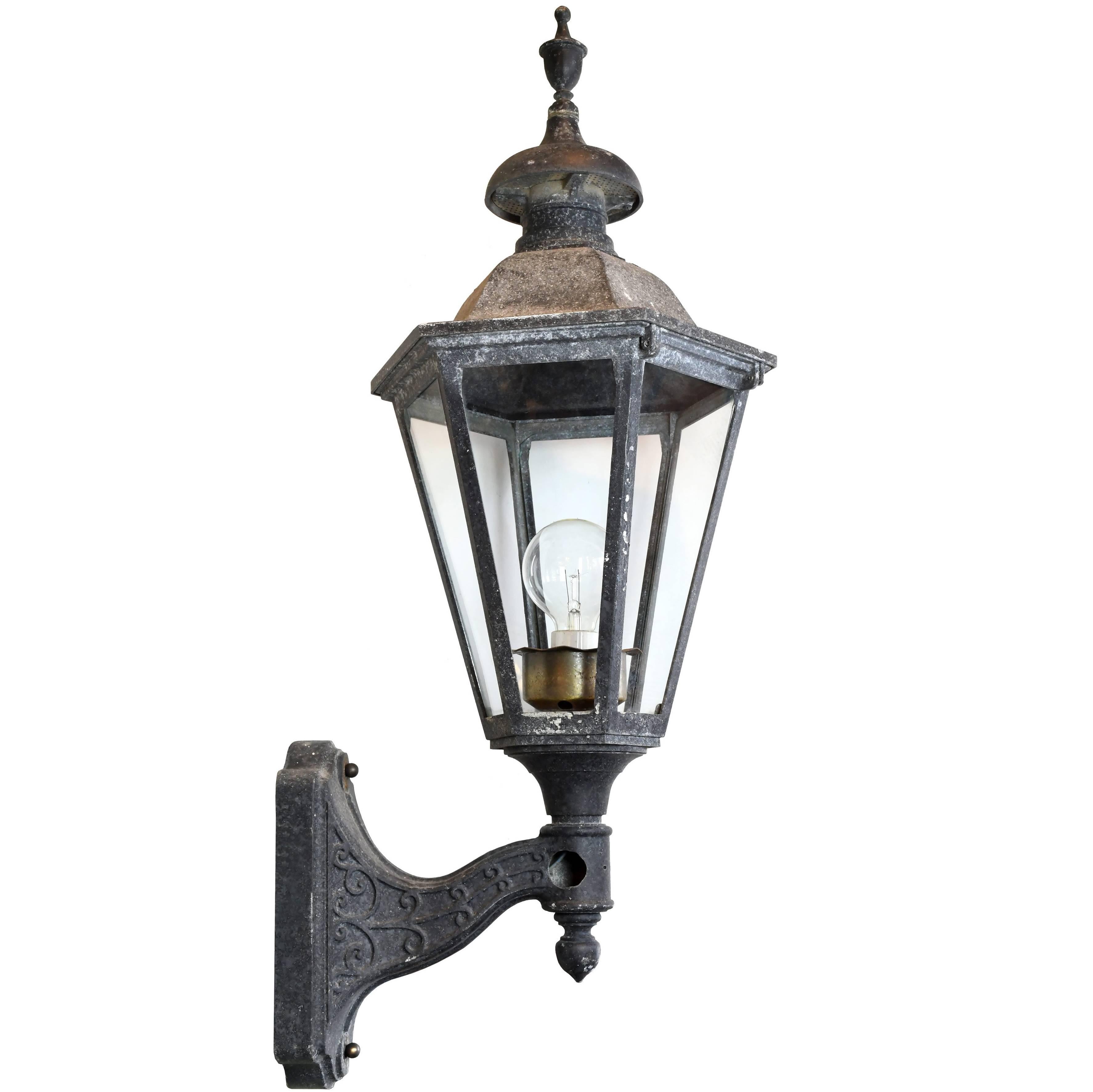 This large exterior sconce features spiraling, vine-like patterns on the arm, six-sided glass panels and textured patina throughout. This striking sconce is sure to make a statement outside any entrance.

circa 1925
Condition: Good
Finish: