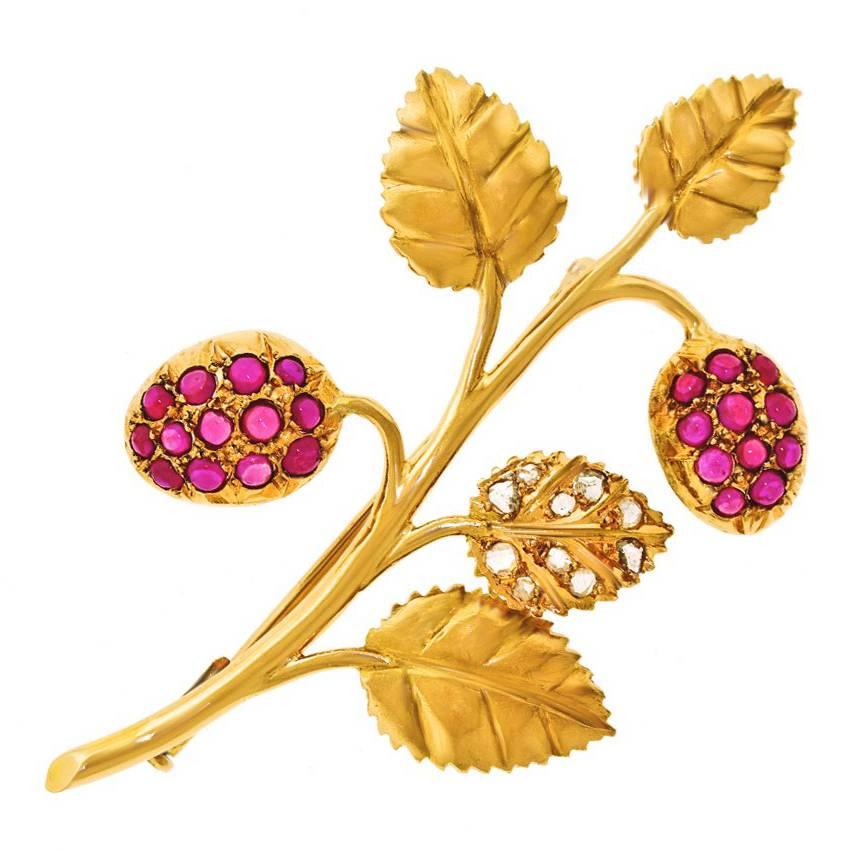 Circa 1920s, 18k, Swiss.  This Art Deco spray of raspberries and leaves has transcendent pared-down modernity redolent of chic moments yet to come. Ruby-set berries are juxtaposed with gold leaves, one mischievously strewn with diamond droplets, to