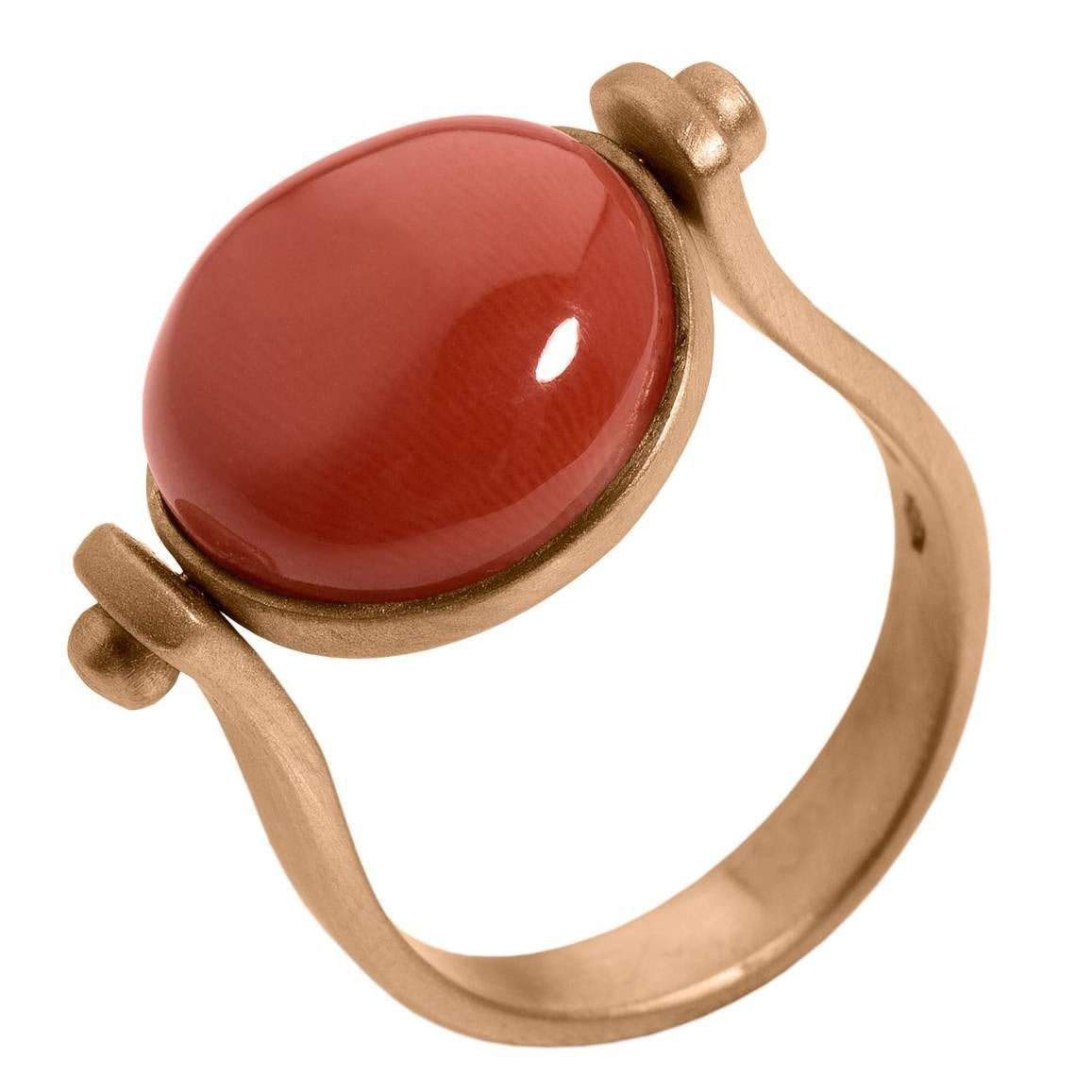 This ring is inspired by my love of ancient Roman jewelry. They used to wear  a ring where its head would be round. 
There's a red round coral as a button above and if you round it you'll have only gold where you can engrave a little phrase or even