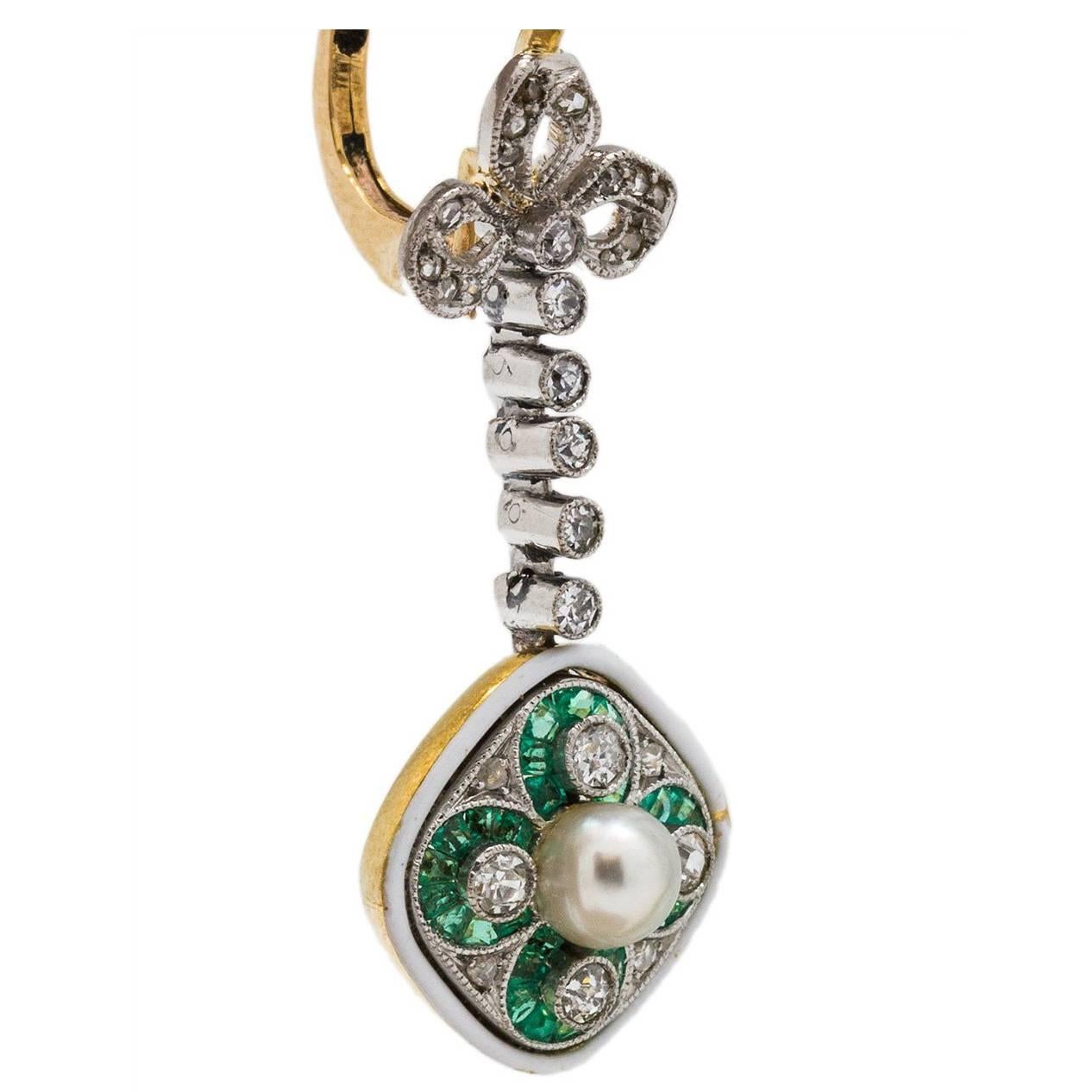Romantic Edwardian pearl, emerald and diamond dangle earrings set in platinum and 18k yellow gold, with whimsical bow tie motif. These lovely earrings are set with a combination of Old European and single cut diamonds, G- H/SI1-I1. Total diamond