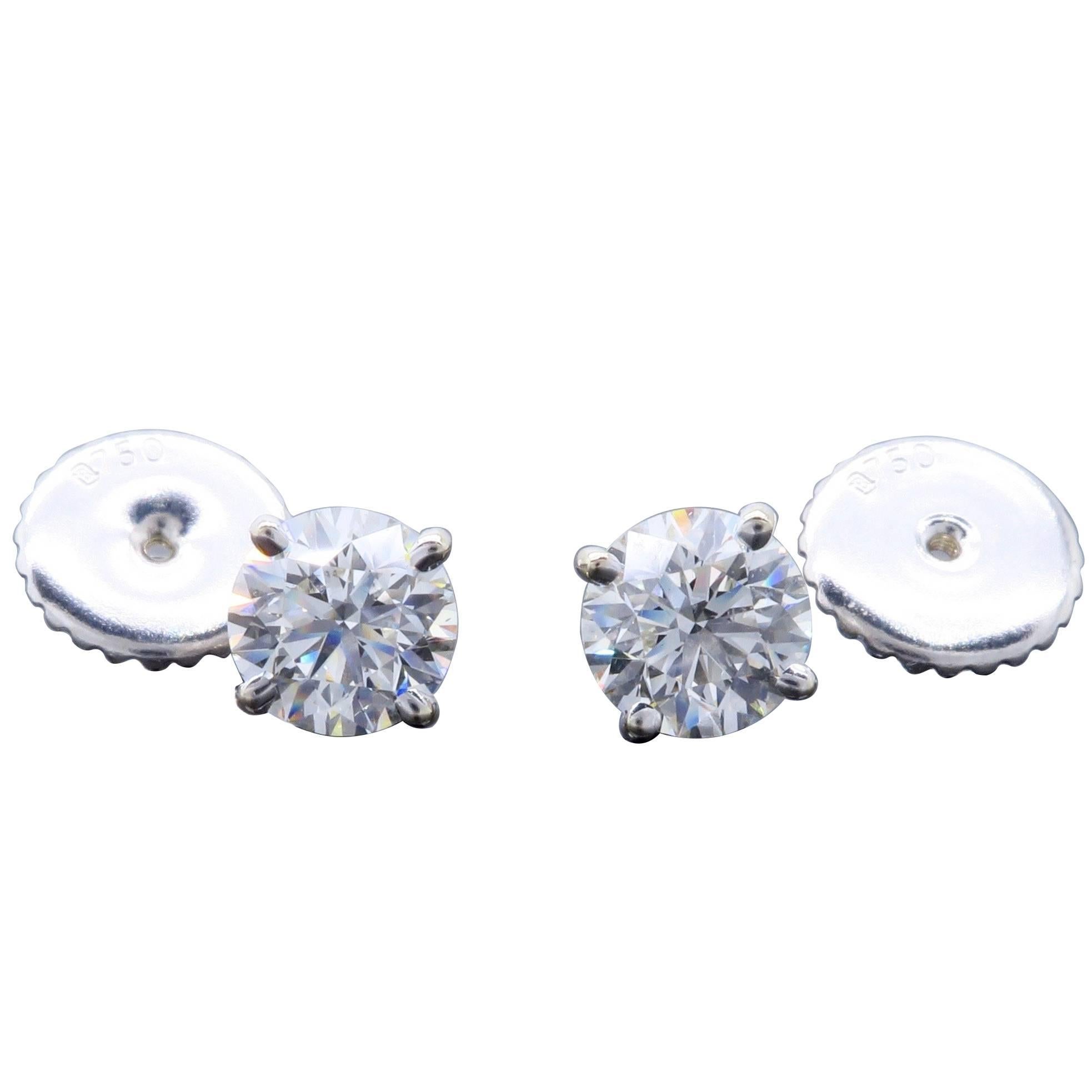 Pair of diamond studs featuring two GIA Certified Round Brilliant Cut Diamonds. Both diamonds are laser scribed with their GIA Certification numbers, GIA # 2106707491 is 1.00CT and has I color and SI2 clarity while GIA # 2106555655 is 1.01CT and has