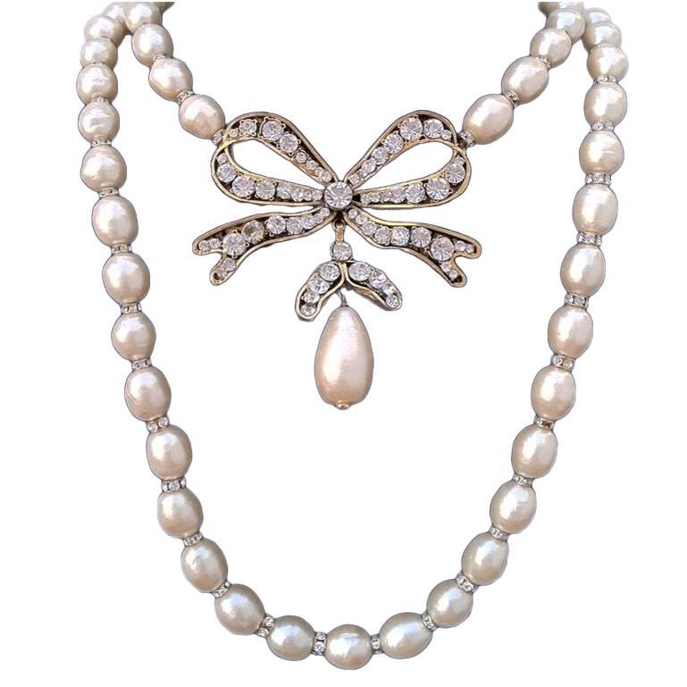 A fine and rare vintage Chanel pearl pendant necklace. Exquisite double strand item features large faux Baroque pearls, crystal rondelles and a gilt metal bow set with Swarovski crystals. Item retains original hook and tail closure plus original