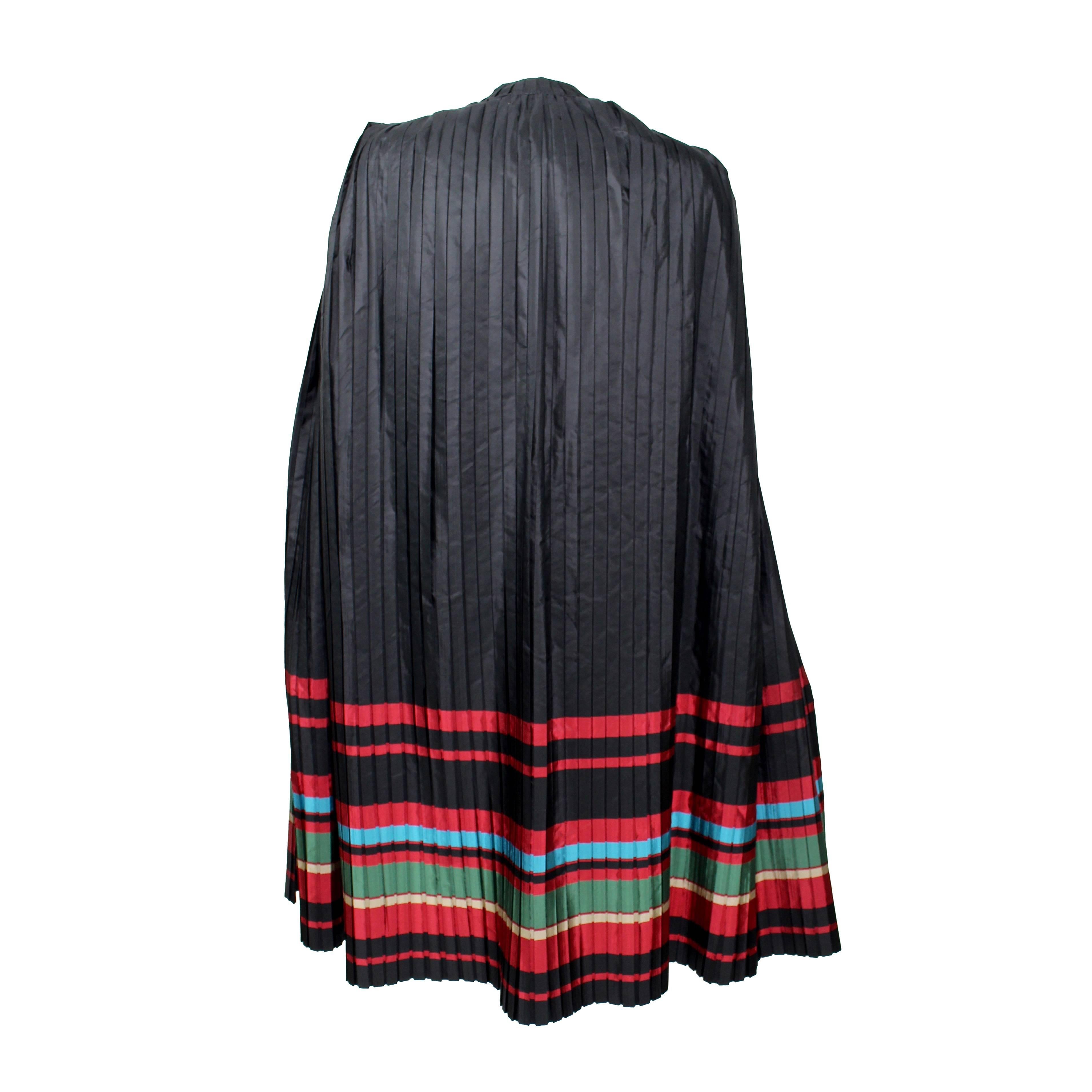 A Fabulous pleated silk cape  from Christian Dior with  a single crystal button closure  at the neck. A vivid display of stripes in red, green gold and blue at the bottom portion. 

Excellent Condition.
Measurements:
cape shoulders measure