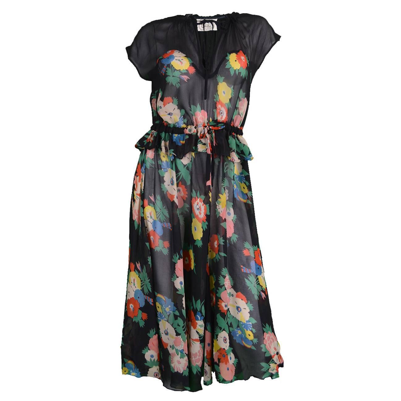 An absolutely incredible vintage dress from the 70s by one of the best and most collectible designers of the 20th Century, Ossie Clark. In a stunning diaphanous black chiffon with an amazing Celia Birtwell floral print throughout. The deep neck and