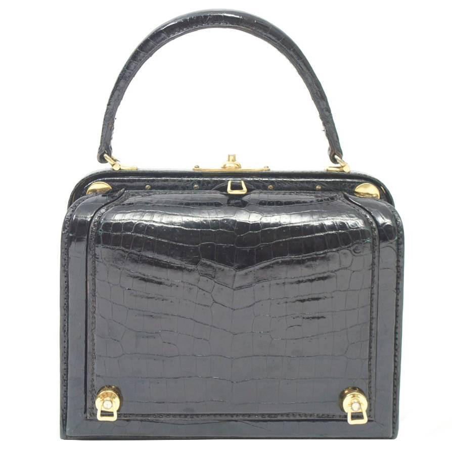 Extraordinary and unique 1960s black crocodile structured handbag with an exterior flap that opens to reveal a red leather compartment. Inside the compartment are four individual and removable leather containers, each impressed with gold lettering