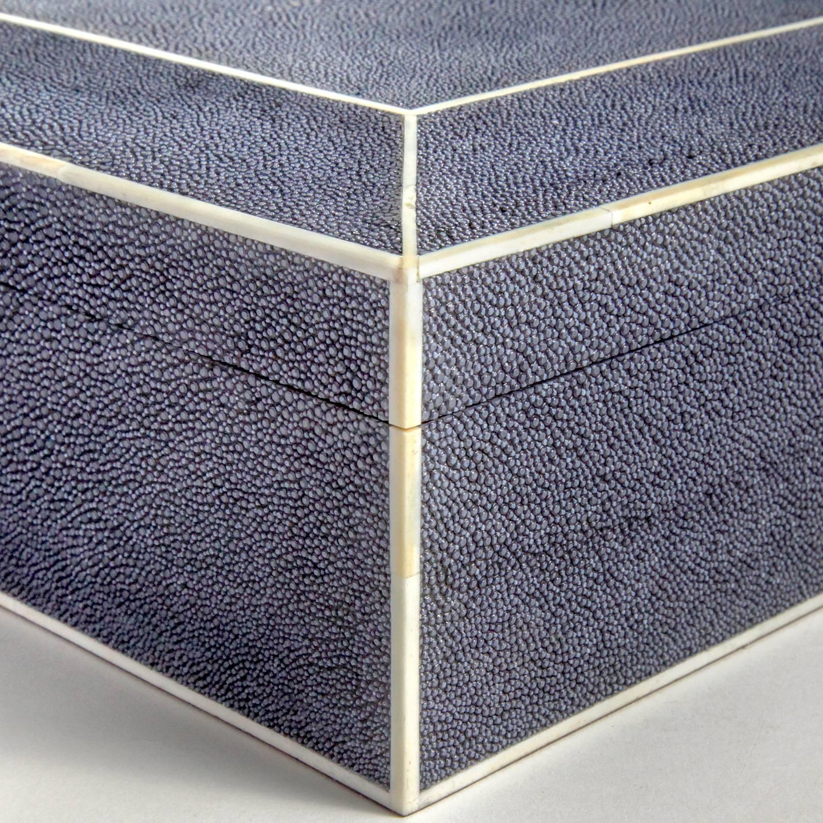 Handcrafted jewelry box with fitted top in tinted navy blue shagreen stingray. Beautifully edged in bone with bone detailing. Inside compartmentalized with beige suede fitted tray. Locks with key. Hand made in France.
