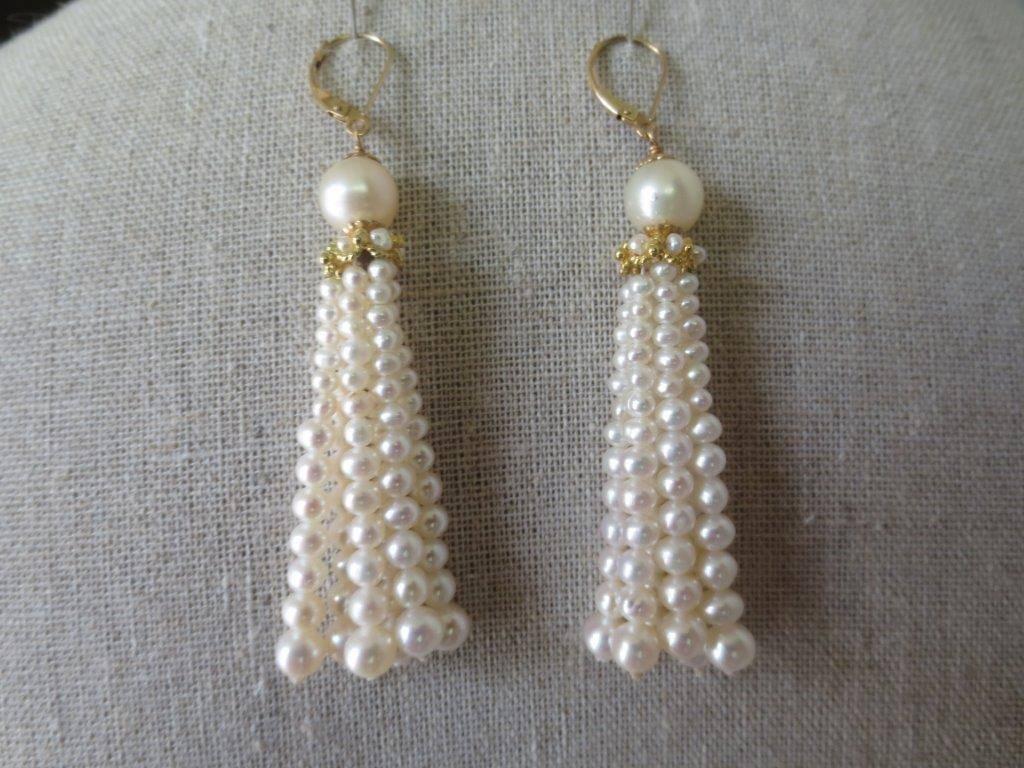 Elegant tassel earrings by Marina J, in strands of cultured pearls, graduated in size from 4 1/2 to 3 mm, and topped by a cultured pearl measuring 6 mm, below which is a gold rondell through which the tassels emanate. The wire is yellow gold. The