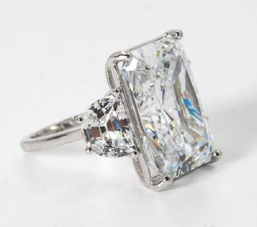 Magnificent faux white 25 carat Radiant Cut diamond ring set with classic half moons side stones. The radiant cut cubic zircon is a wonderful high quality white color that reflects and sparkles exactly like a gem!

Measures 7/8th inch by 6/8th