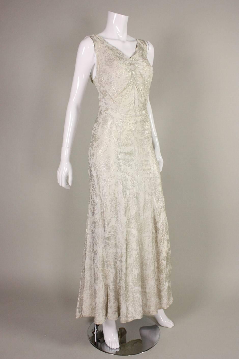 Vintage gown dates to the 1930's and is made of cream metallic lamé fabric.  Sleeveless bodice has v-neck and center front ruching at bust.  Fantastic seam detailing around waist, hips, and down the center back.  Unlined, but comes with slip. 