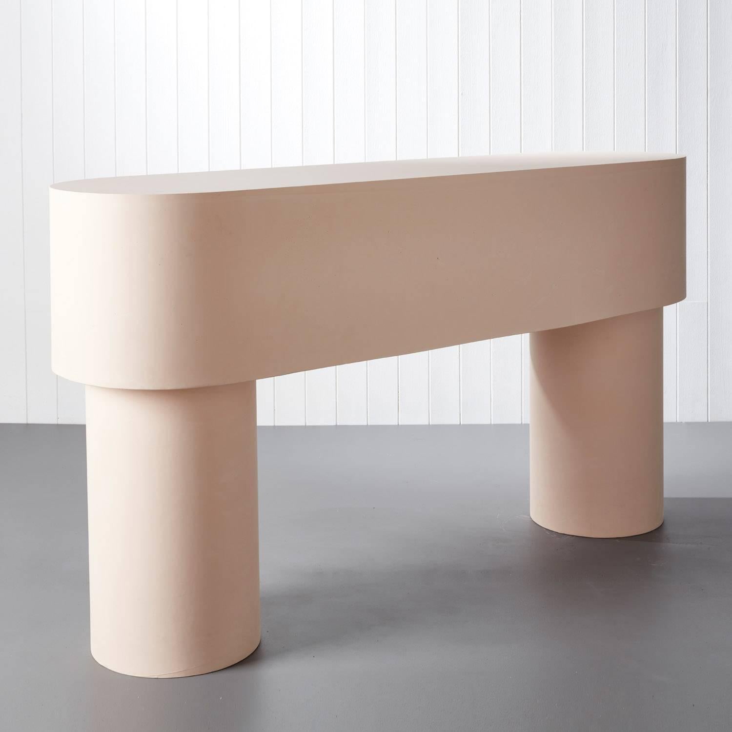 Pilotis console table by Malgorzata Bany, a light pink jesmonite console table with a smoothened surface and rounded corners. The structurally solid piece takes inspiration from the concept of pilotis- architectural support columns that