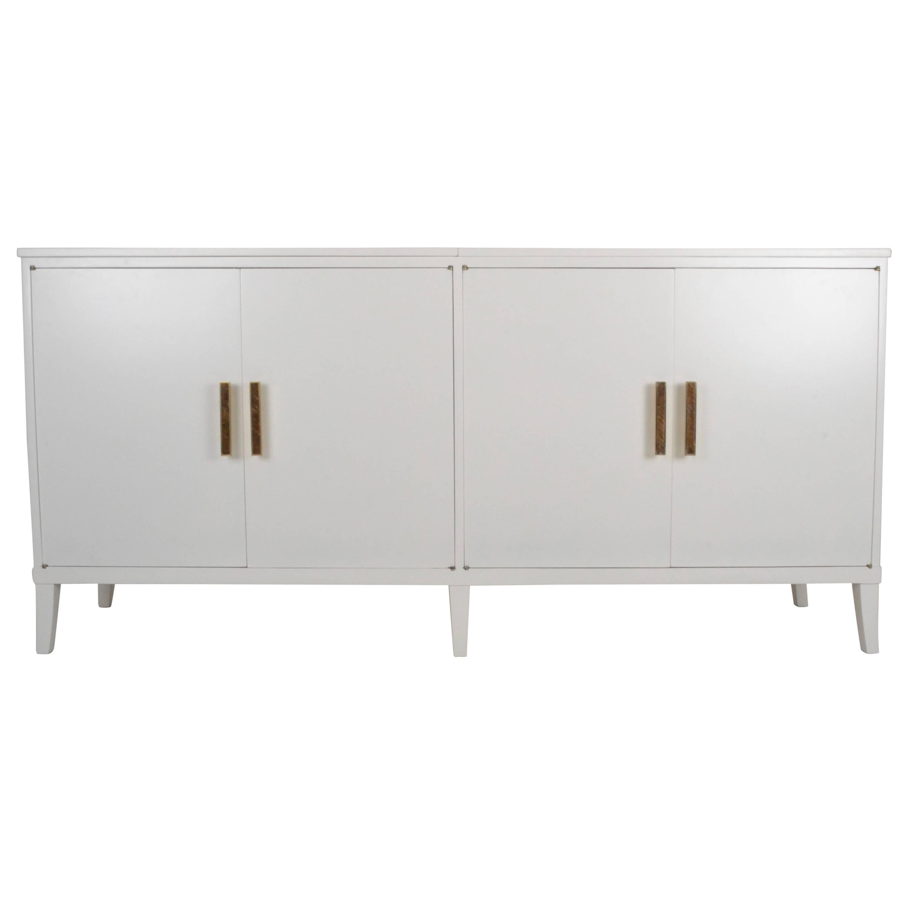 Sleek white cabinet with great lines. Left top opens to a hidden bar with bottle well and interior light. Right cabinet features built in wine rack. Great shapely legs and, maybe best of all, wonderful brass and inlaid enamel handles. Newly
