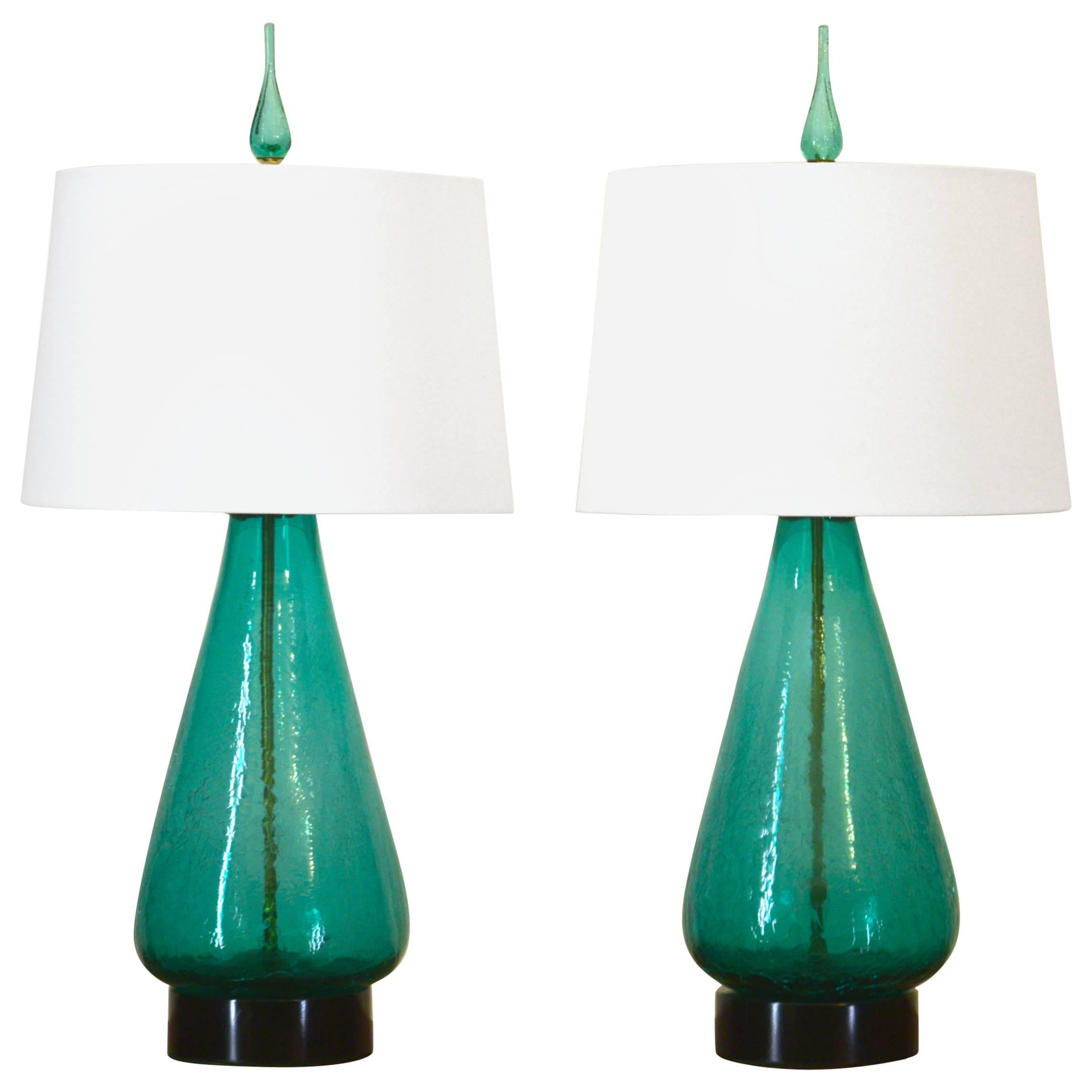 A delightful pair of Blenko glass table lamps from the early 1960s in crackled sea green.  Positioned on black enamel metal bases with all new wiring and felt. All original sockets and harps featuring three-way power sockets and 12 foot table lamp
