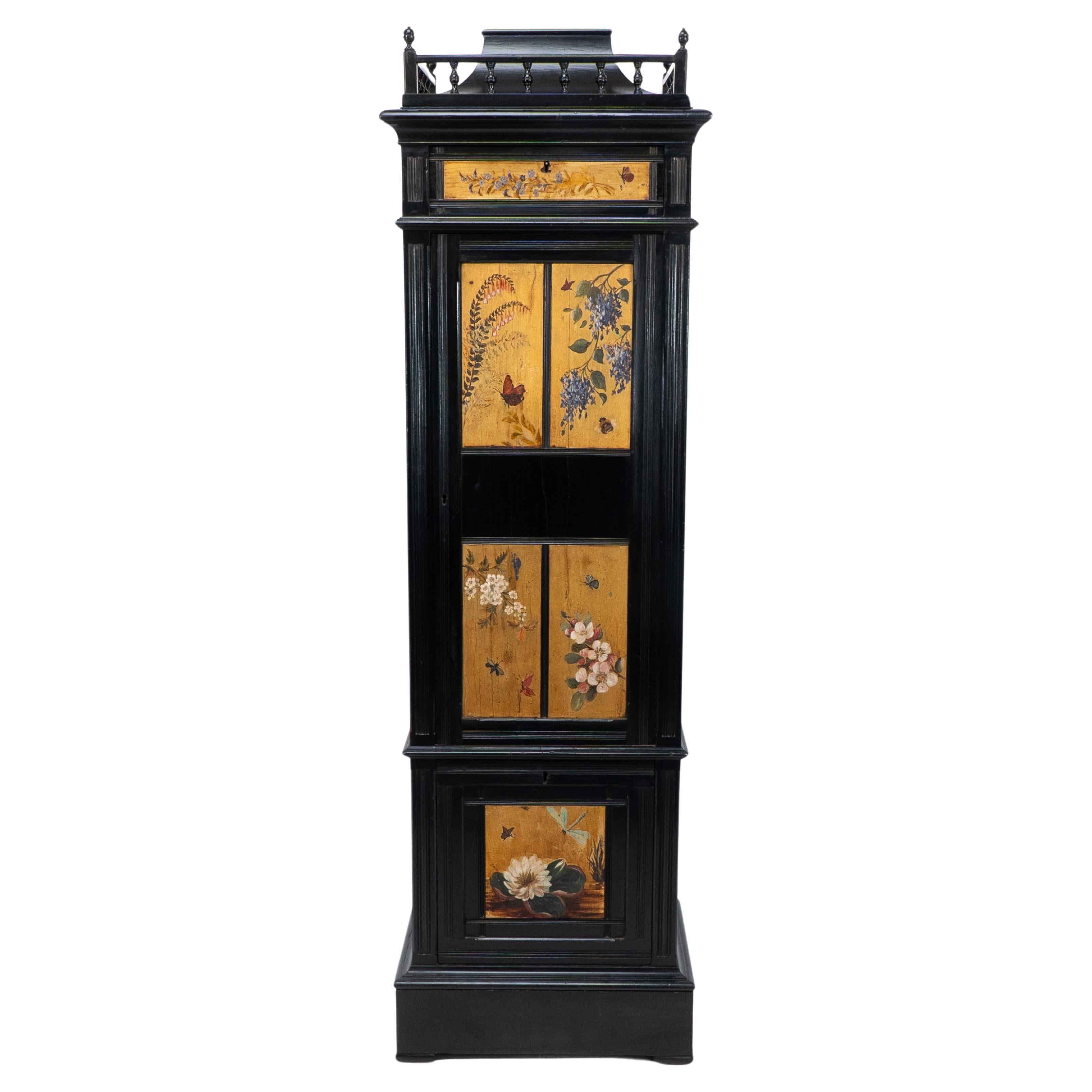 A rare Aesthetic Movement ebonized polychrome painted Humidor with a shaped display plinth to the top, surrounded with a turned gallery, and an upper compartmented drawer hand painted with a spray of flowers and a hovering butterfly. On the main