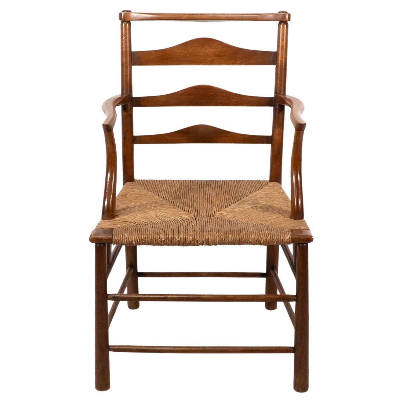 C R Ashbee. An Arts and Crafts rush seat ladder back armchair with arms that follow down through to the side stretchers. Ashbee used this version of armchair for his family home, offices and personal workshop that he built at 37 Cheyne Walk Chelsea,