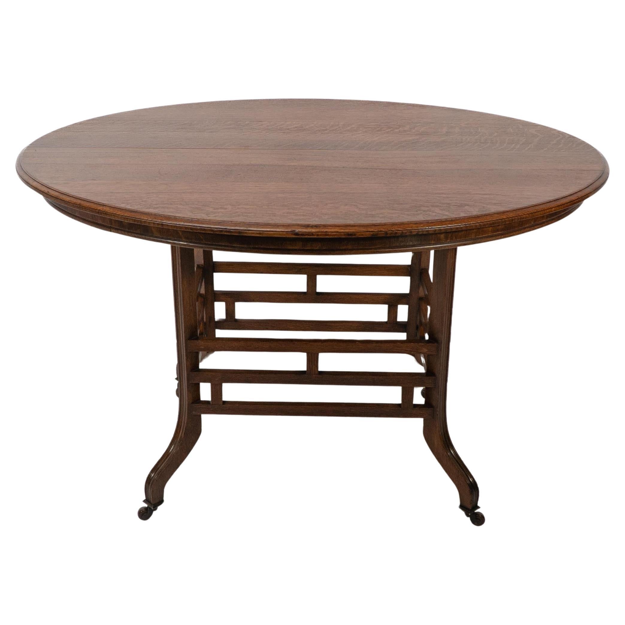 Lambs of Manchester, stamped Lambs to the underside. A rare Anglo-Japanese quarter sawn oak oval centre table with wonderful wild figuring to the top. The four legs with scribed tramline decoration to the outer edges united by an intricate lattice