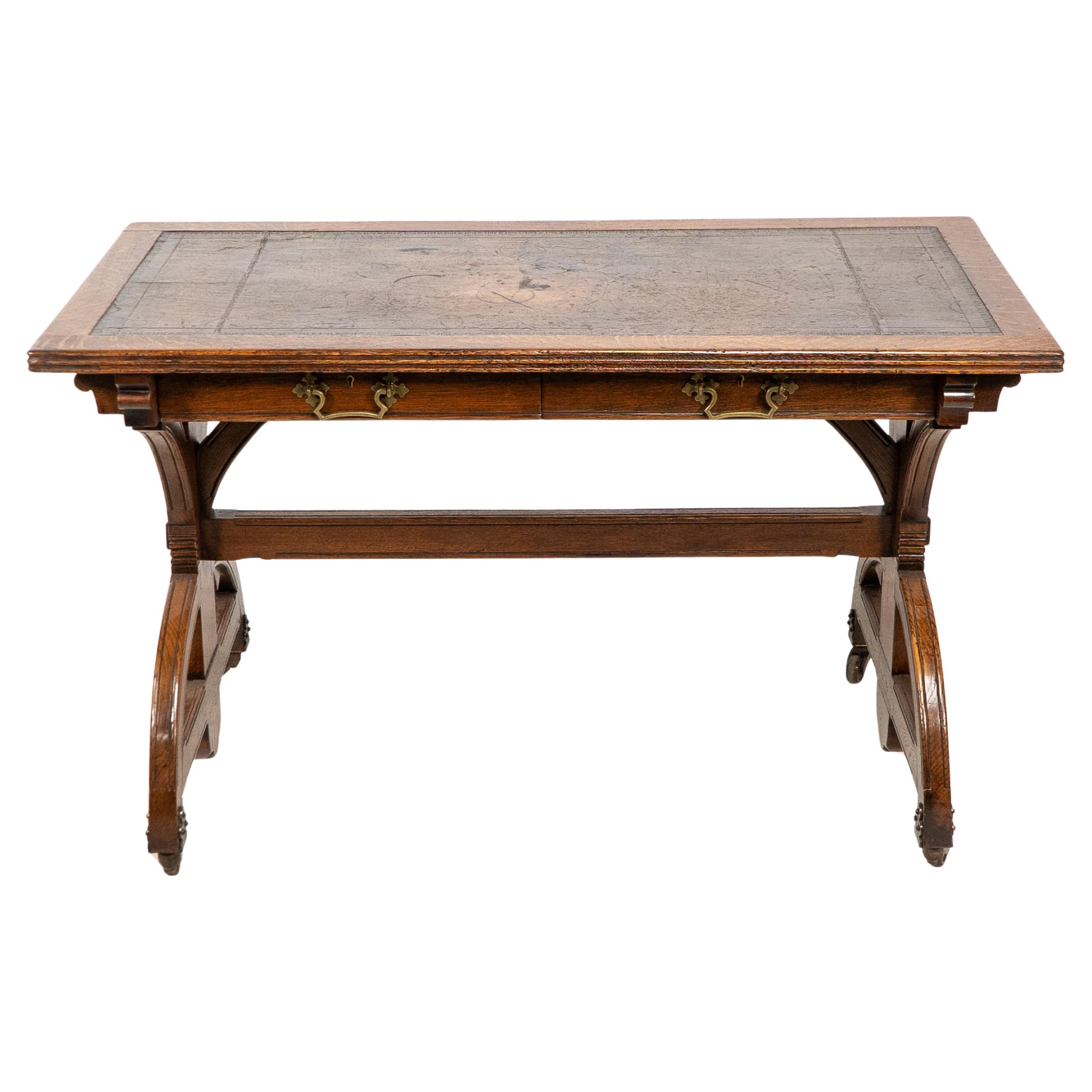 Bruce Talbert attributed possibly for Cox and Sons. A good period Gothic Revival oak desk with the original leather writing area and Y shaped supports below united by a high stretcher double D end feet with decorative brass castors.The locks stamped