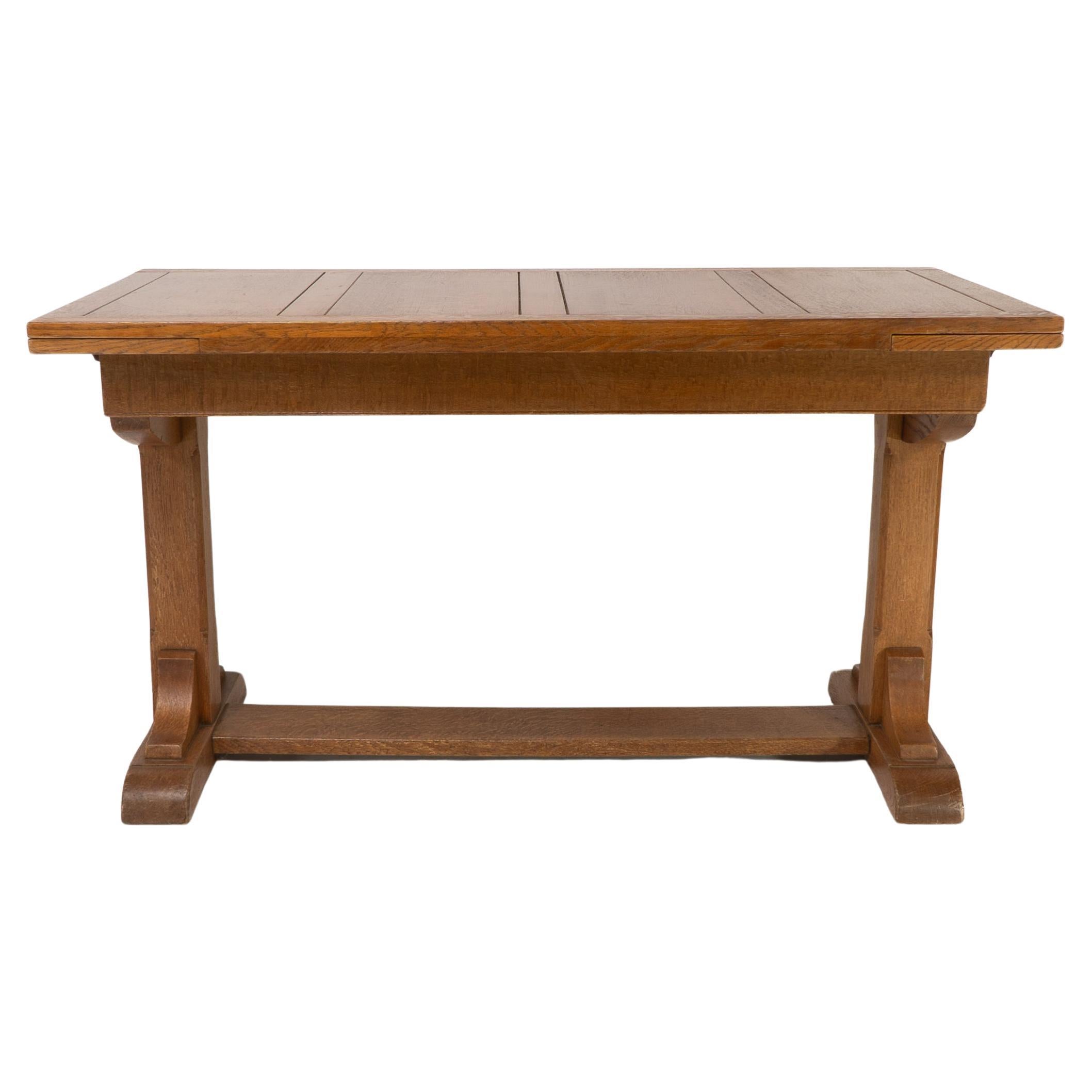 Heals and Son. An Arts and Crafts narrow oak extending dining table with two leaves.Dimensions: Height 76 cm x Width 137 cm x Depth 69 cmExtended: Height 76 cm x Width 183 cm x Depth 69 cm
