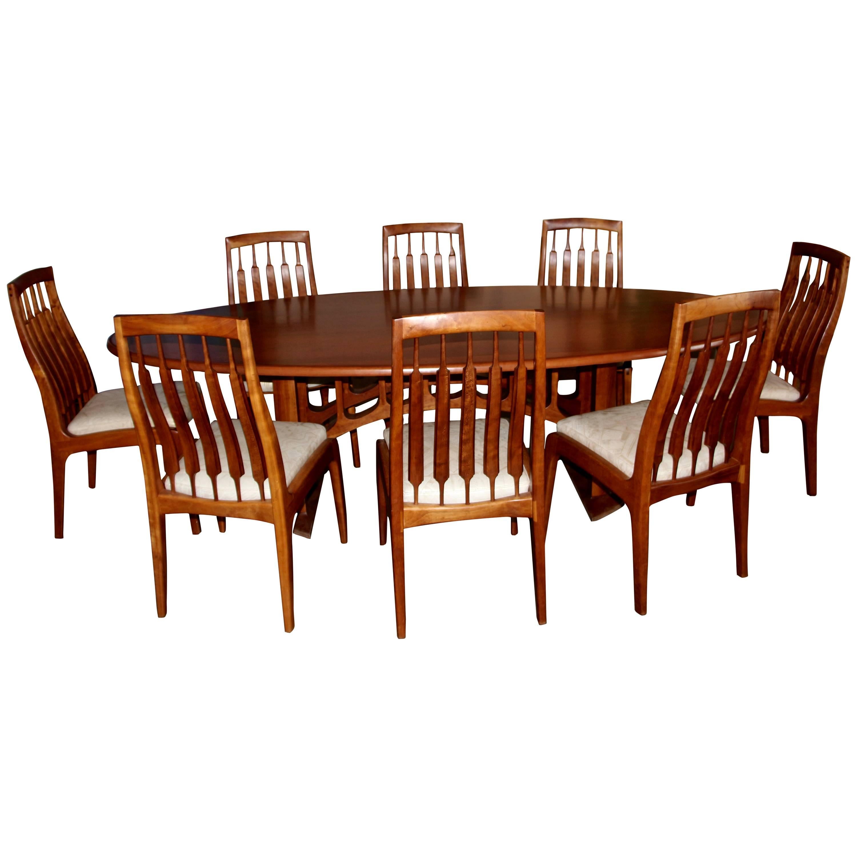 A custom-made sculptural dining table with eight chairs custom-made by the noted California Craftsman Randy Bader. This table is solid wood. The chairs are dated Sept 1994. The seats are covered in hand tooled leather. This is a spectacular dining
