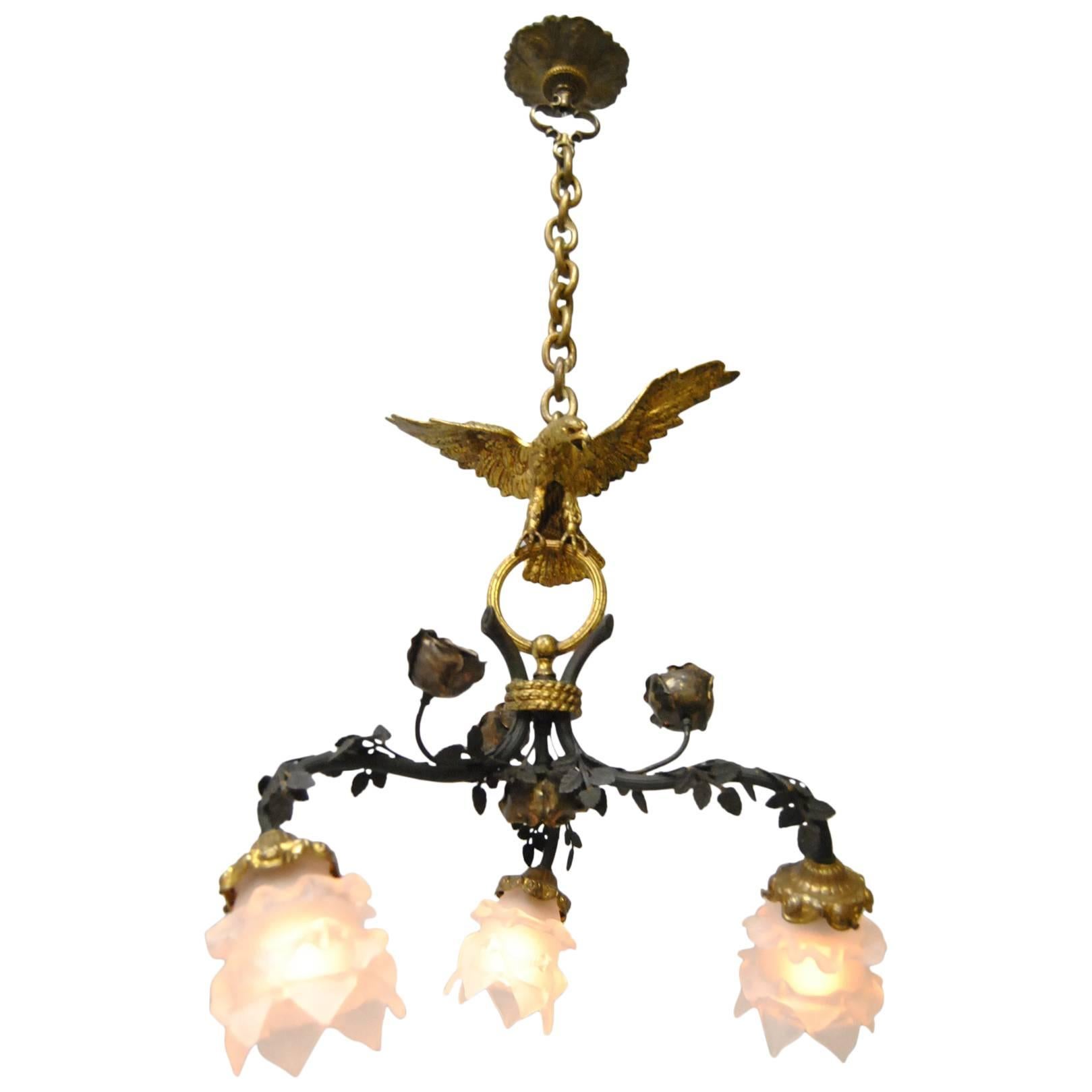 Gorgeous French Empire bronze chandelier with Eagle.  Eagle with outspread wings sits atop three vines.  Bronze shades holders have raised flowers. Each arm holds a flower form shade (new). Fixture has been completely rewired and is ready for use.