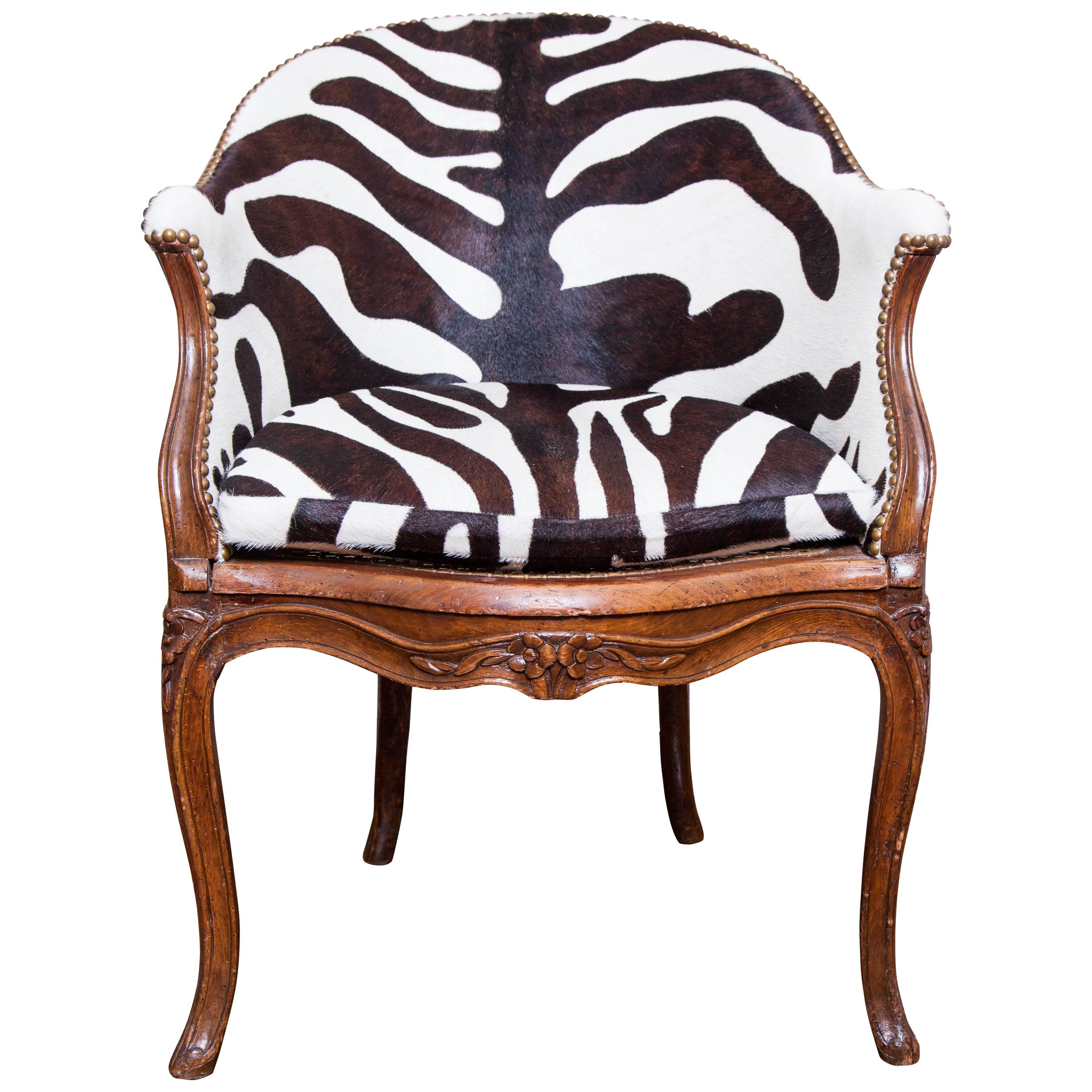 The floral carved walnut desk chair with caned back and seat, upholstered with zebra pattern dyed calfskin, with floral carving. small opening in the caning which is visible in the photo. 
