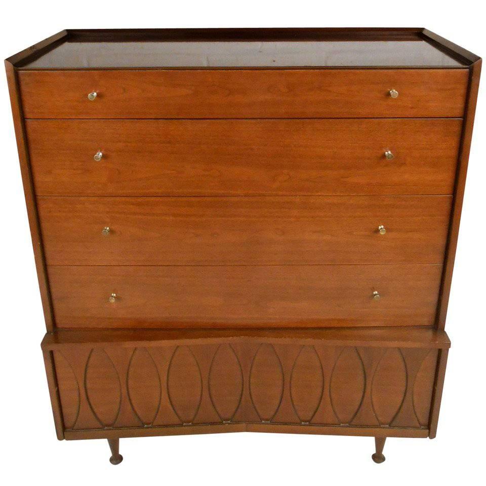 This stylish vintage highboy dresser features Mid-Century walnut veneer, uniquely sculpted drawer fronts, tapered legs, and raised edges. Spacious drawers allow for plenty of bedroom storage, while the retro style makes an impressive addition to any