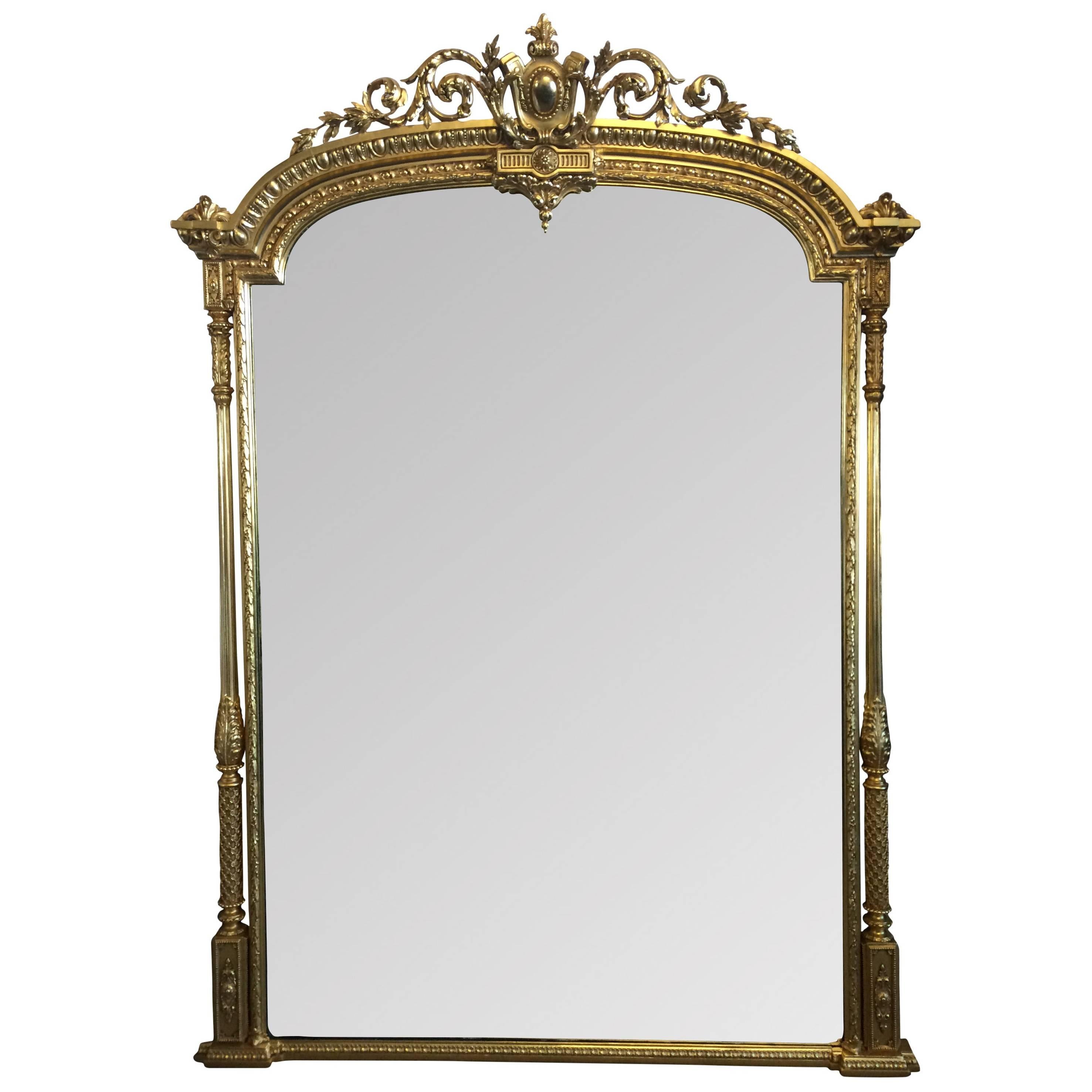 A truly stunning, large mid-19th century English Adams Style gilt framed arch top overmantel mirror with cartouche crest, flanked by ornate columns. In excellent condition, having been regilded in 23.5-carat gold by Master Guilders. 