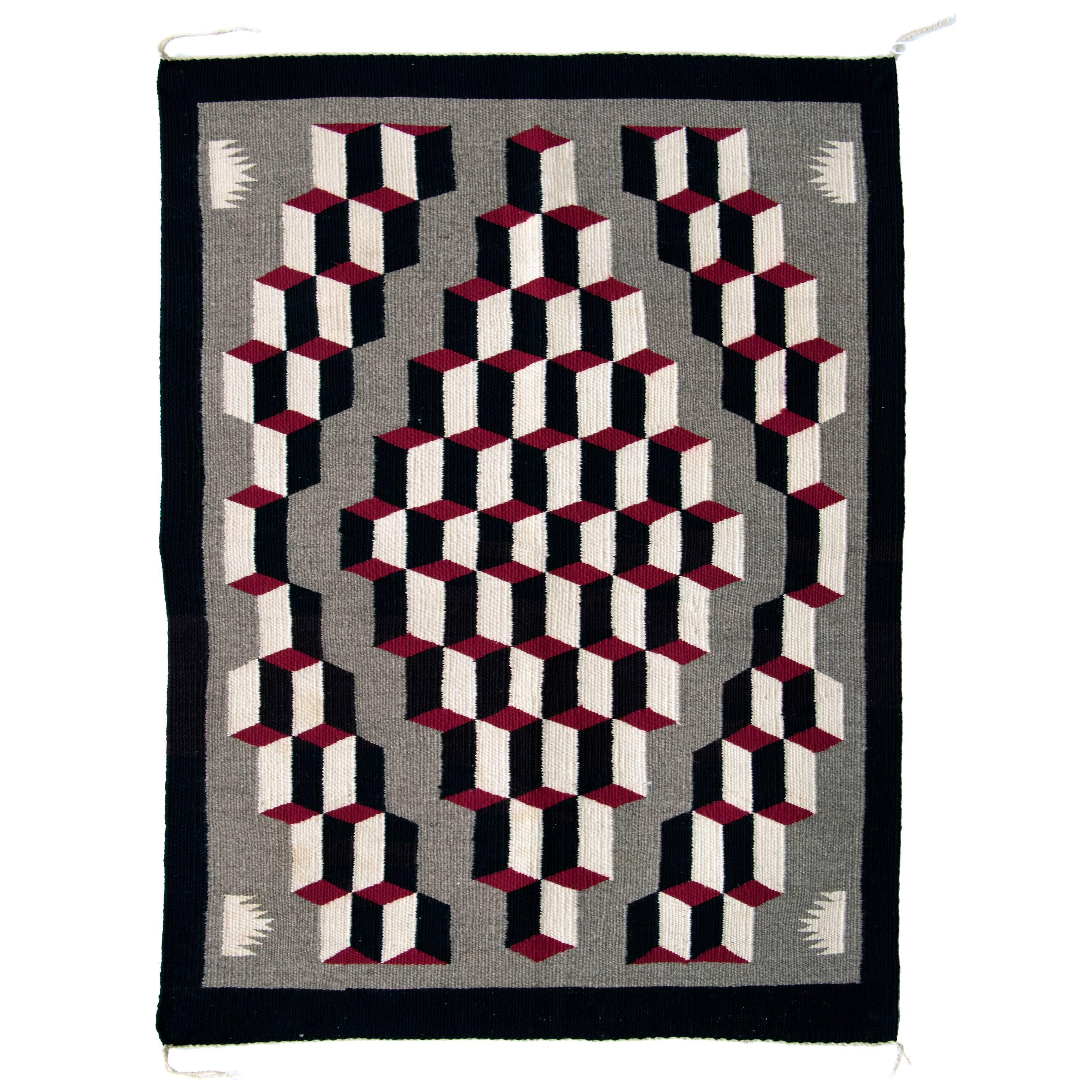 Woven of native hand-spun wool in natural black, ivory and gray fleece with aniline dyed red. The striking composition is referred to as an Optical or Tumbling Block Pattern

This piece is well suited for use as an area rug, wall hanging or