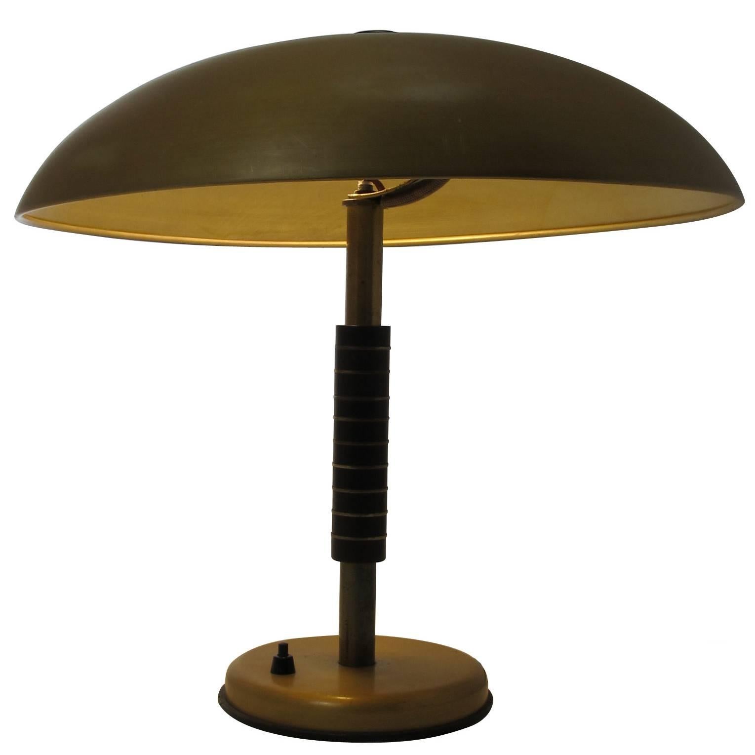 This Art Deco table lamp was produced by SbF in 1944. It features a gold lacquered metal shade with a metal and bakelite stand. This lamp has been rewired.