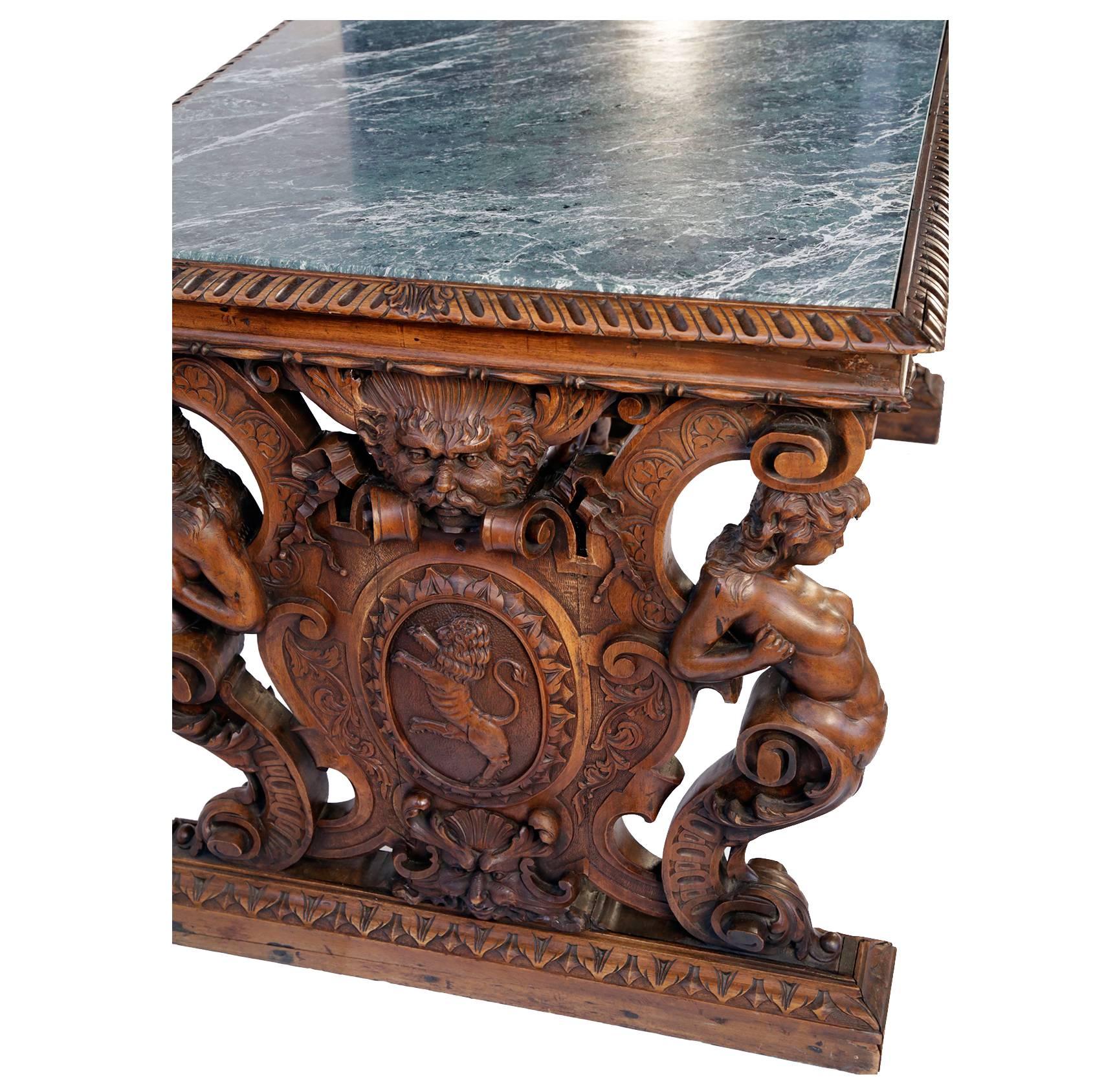The rectangular top with gadrooned border, fitted with green veined marble, over a trestle base carved with female terms centering masks and an oval cartouche relief carved with a lion passant, joined by a stretcher carved with a pair of putti