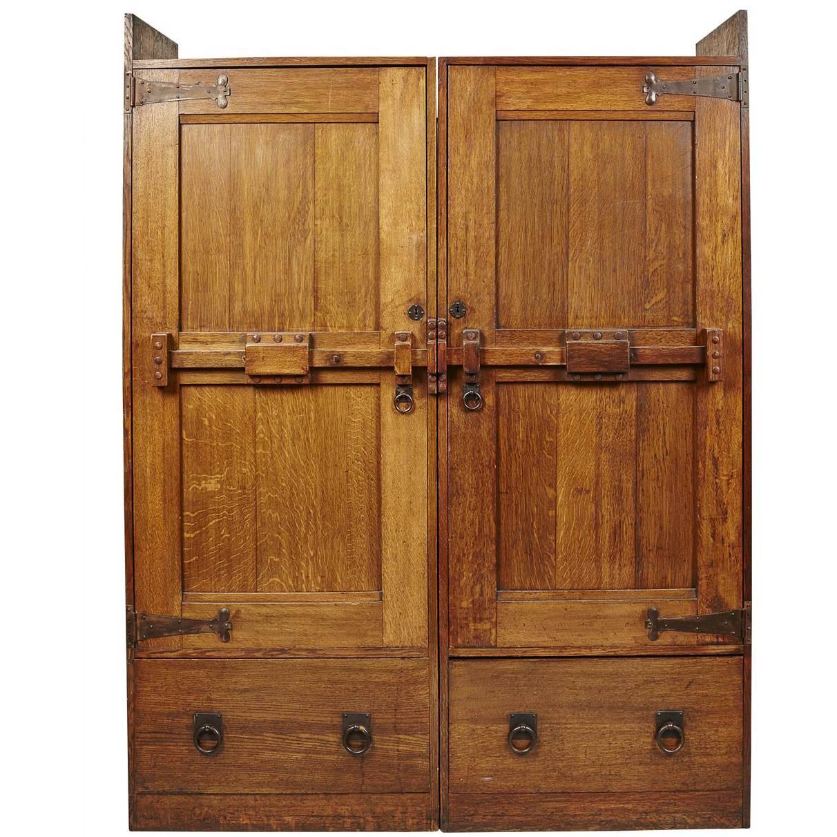 Wylie & Lochhead. A Large Arts & Crafts Oak Wardrobe With Stylised Iron Hinges