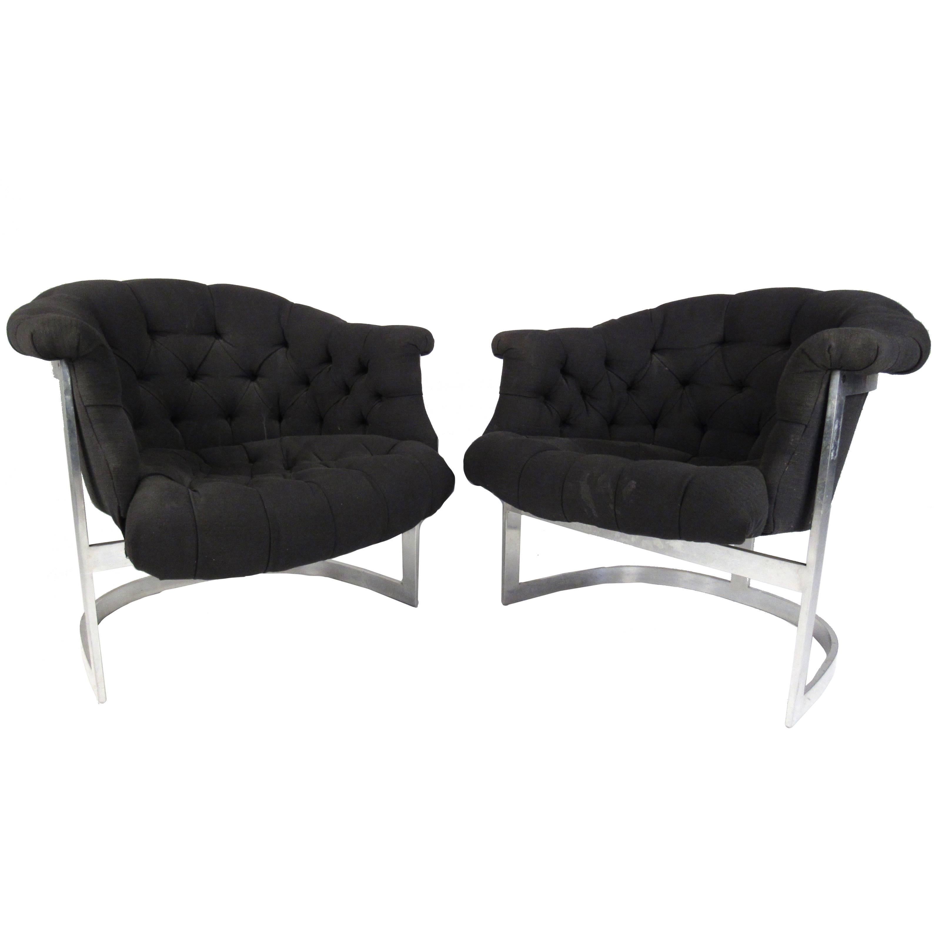 This pair of vintage modern tub style lounge chairs feature the unique barrel back style design of Mid-Century master Milo Baughman. The overstuffed seats are covered in tufted black upholstery and boast winged arm rests. The chrome cantilever base
